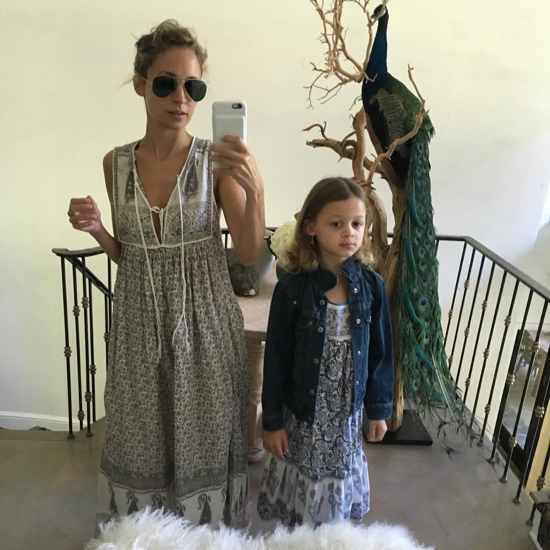 Nicole Richie takes a mirror selfie while standing beside Harlow Winter Kate Madden indoors. With a peacock displayed behind them, the image shows the mother-daughter pair dressed in coordinated bohemian-style outfits. | Source: Instagram/nicolerichie and joelmadden