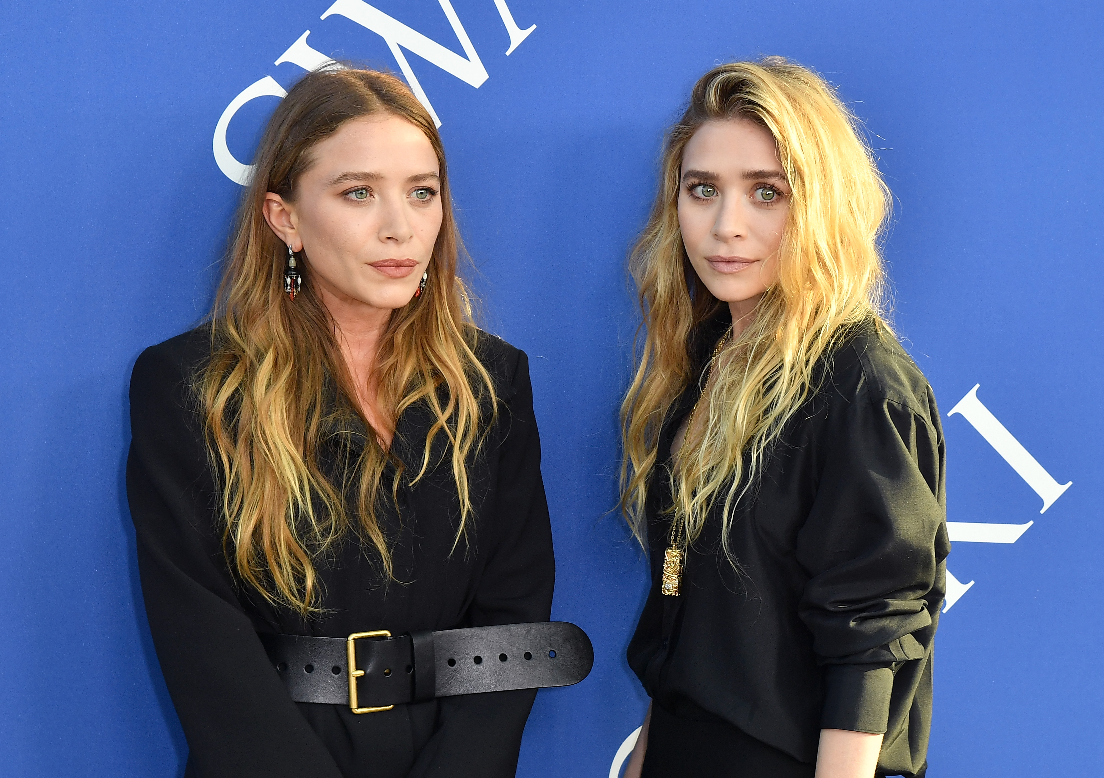 Sharp jawlines, prominent cheekbones, and piercing, direct gazes defined 31-year-old Mary-Kate and Ashley Olsen at the June 4, 2018 CFDA Fashion Awards, where their expressive faces were framed by long, tousled blonde tresses and minimalist black ensembles featuring statement belts and pendant necklaces.