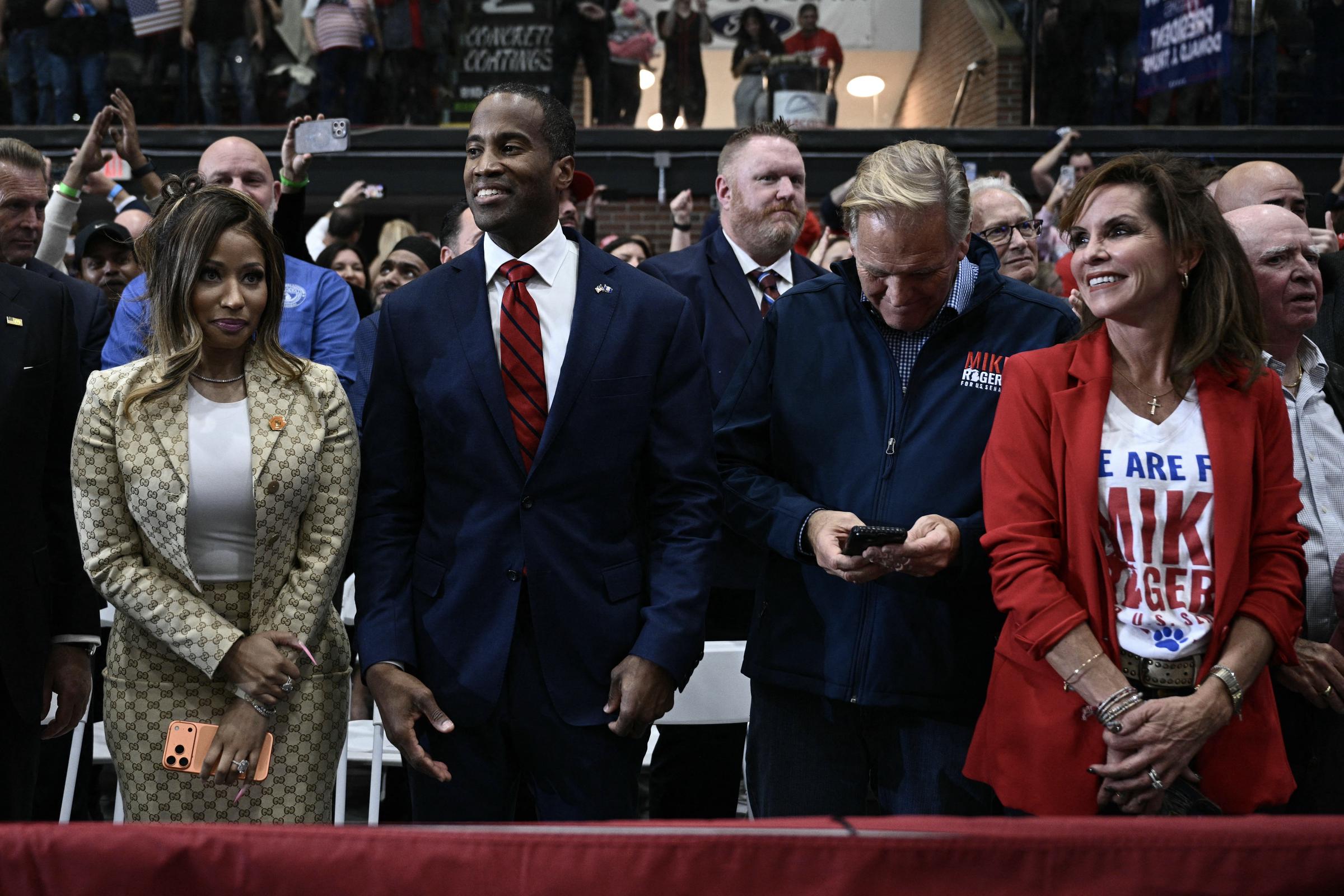 Nicki Minaj stands among other guests at the rally, alongside supporters of Michigan Senate candidate Mike Rogers. The event brought together political figures and campaign supporters, with spectators raising their phones to capture the occasion. | Source: Getty Images