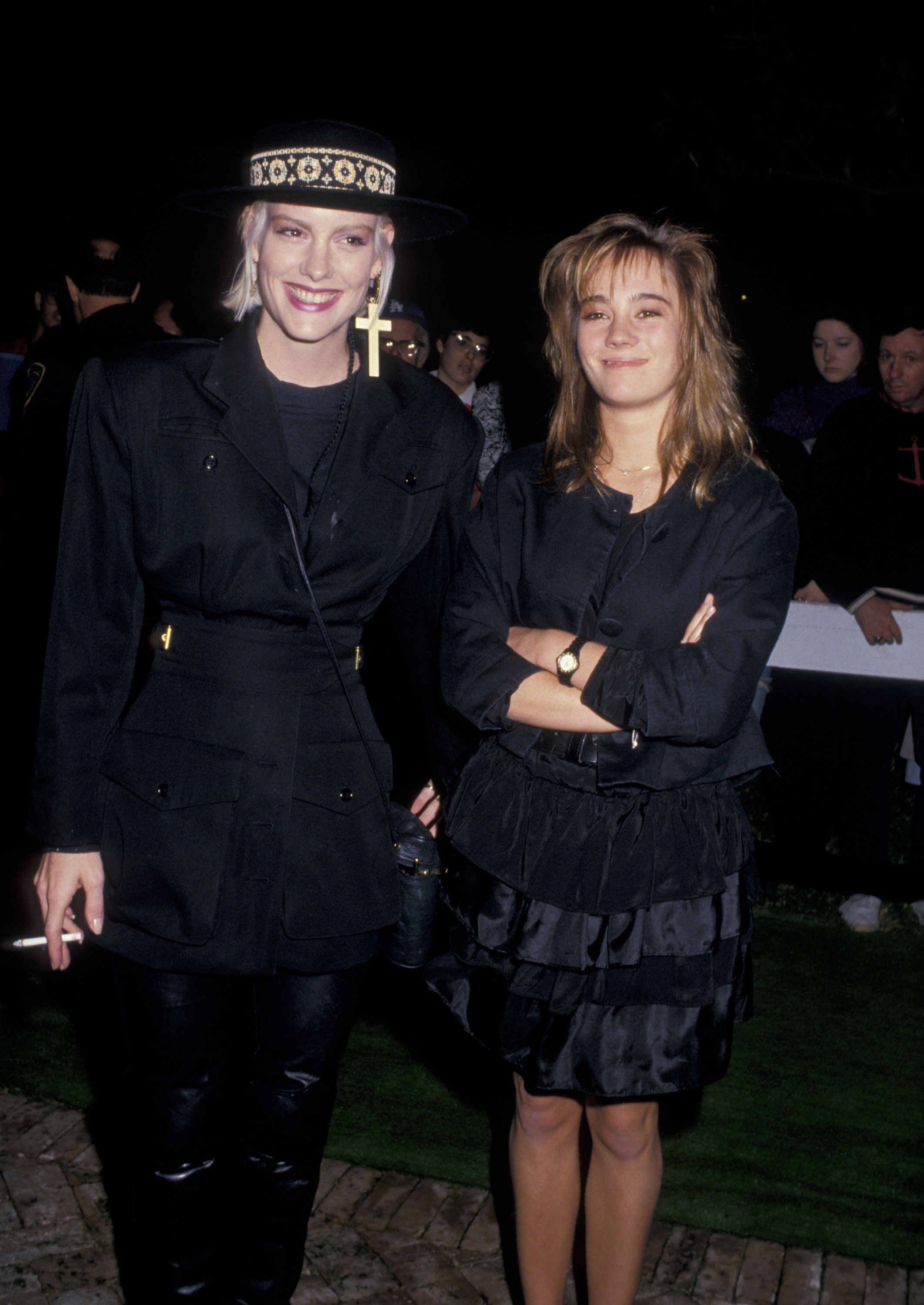 Katie Wagner and Natasha Gregson Wagner attend a U2 party at Jane Fonda's Beverly Hills home on November 20, 1987. Katie wears a black outfit with a wide-brimmed hat and cross earrings, while Natasha stands beside her in a tiered black skirt and matching jacket.