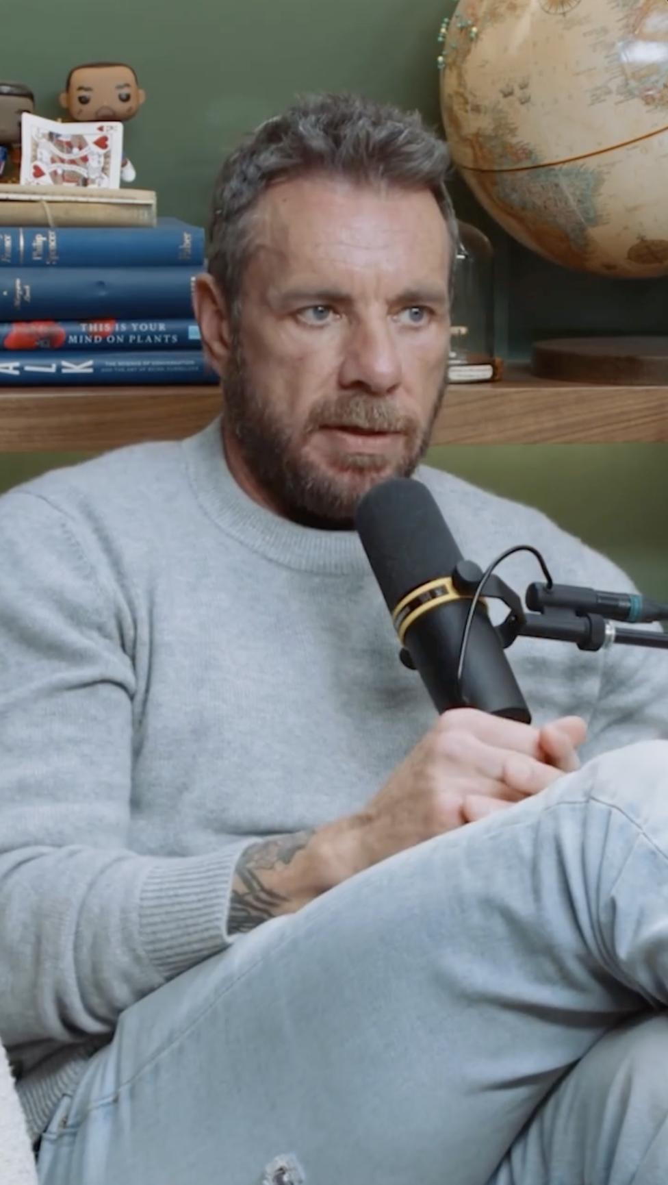 Dax Shepard sits in his podcast studio, beard neatly trimmed and eyes focused as he speaks into the microphone. The soft sweater and visible tattoo hint at a more grounded, mature era. | Source: Instagram/daxshepard