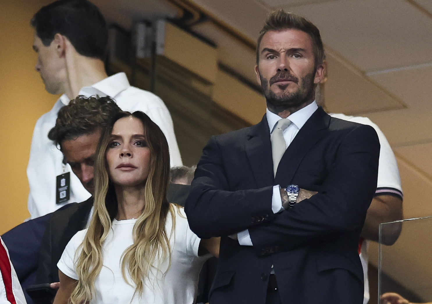 A focused Victoria Beckham, wearing a relaxed white top and jeans, stands beside David Beckham in his tailored navy suit as they watch football's biggest night with intent looks. | Source: Getty Images