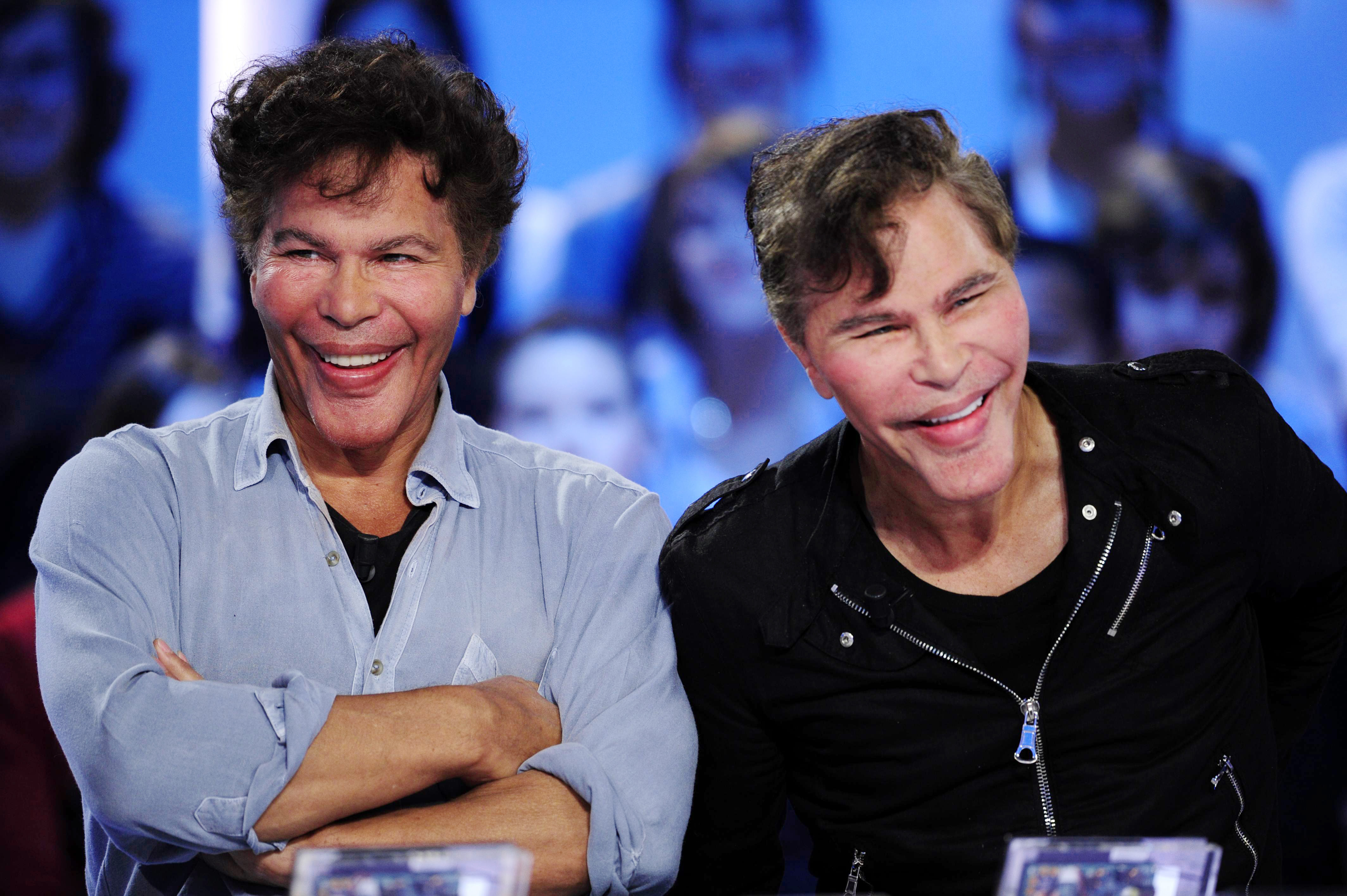 French journalists Igor and Grichka Bogdanoff laugh heartedly as they appear on the set of Canal+’s “Le Grand Journal” in Paris. Their faces display more noticeable transformations, with fuller lips, puffier cheeks, and a more sculpted chin.