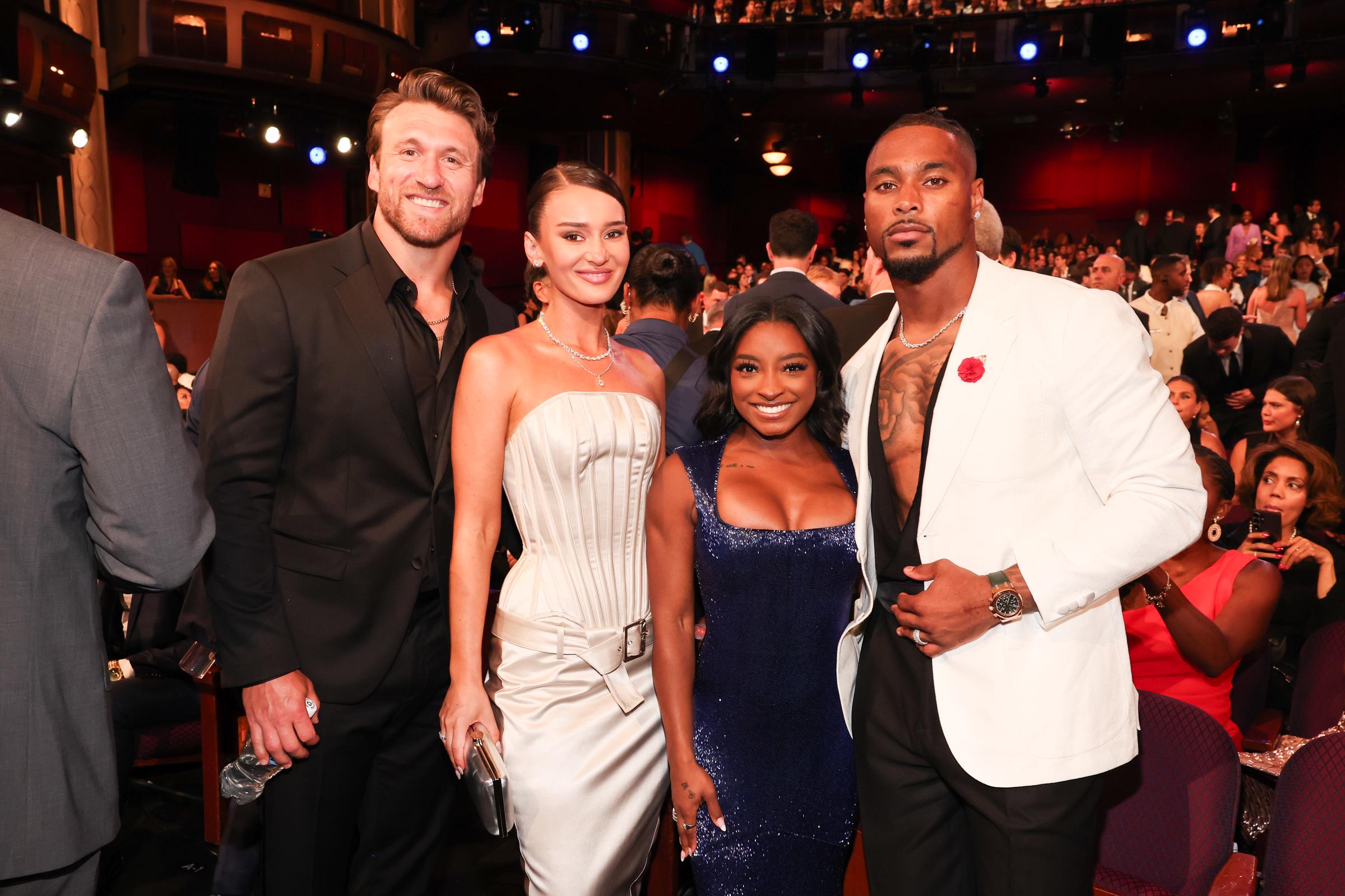 Kyle Juszczyk, Kristin Juszczyk, Simone Biles, and Jonathan Owens pose together inside the Dolby Theatre during the 2025 ESPY Awards. Biles and Owens stand closely side by side, while the Juszczyks, dressed in coordinated black and white formalwear, flank the couple for the group photo.