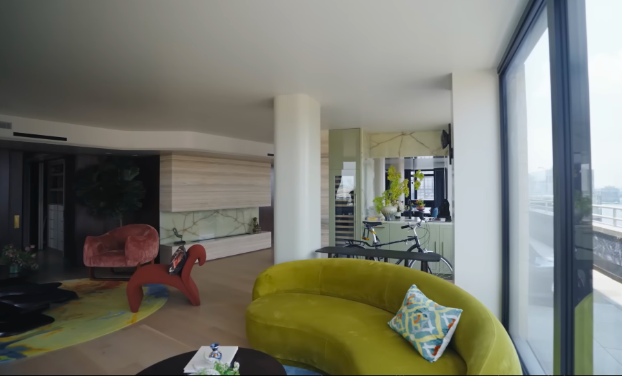 The apartment's open sight lines were carefully planned so one space naturally leads into the next. Even from the green sofa, the eye travels past the fireplace and into the kitchen beyond. | Source: YouTube/Architectural Digest