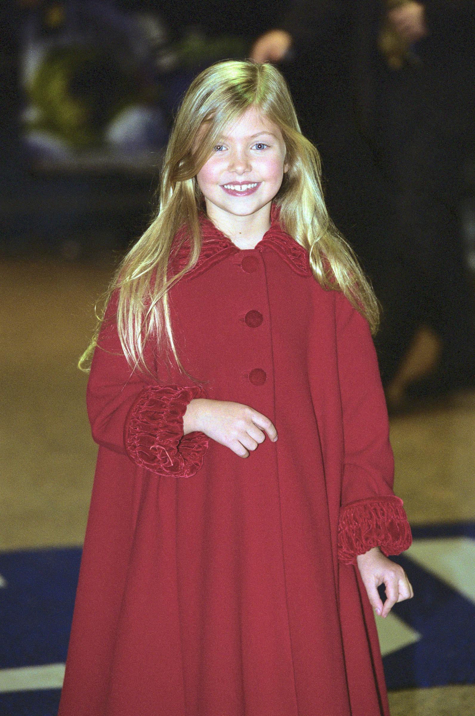 Taylor Momsen at the premiere of "How the Grinch Stole Christmas," beaming with a bright smile and shiny blonde hair parted down the middle, while stunning in a maroon outfit.