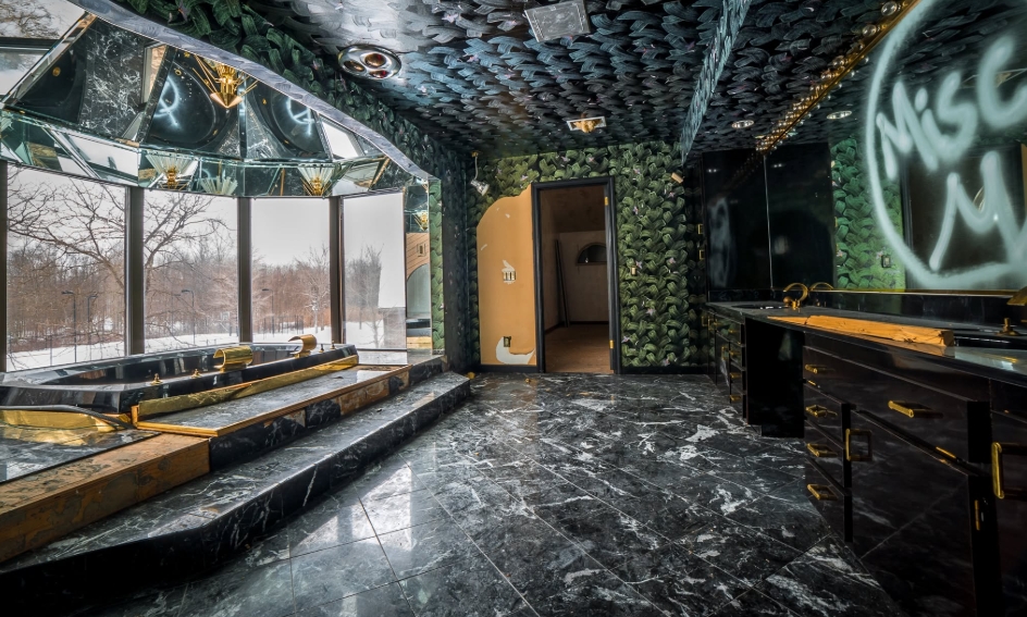 Black marble surfaces, gold-colored fixtures, mirrored panels, and densely patterned walls remained inside a bathroom at Mike Tyson's former Ohio home. The elaborate space reflected the lavish aesthetic once found throughout the estate, where luxury extended beyond its five bedrooms to include a Jacuzzi and other extravagant amenities. By this stage, visible damage also revealed the property's years of neglect. | Source: Facebook/Johnny Joo