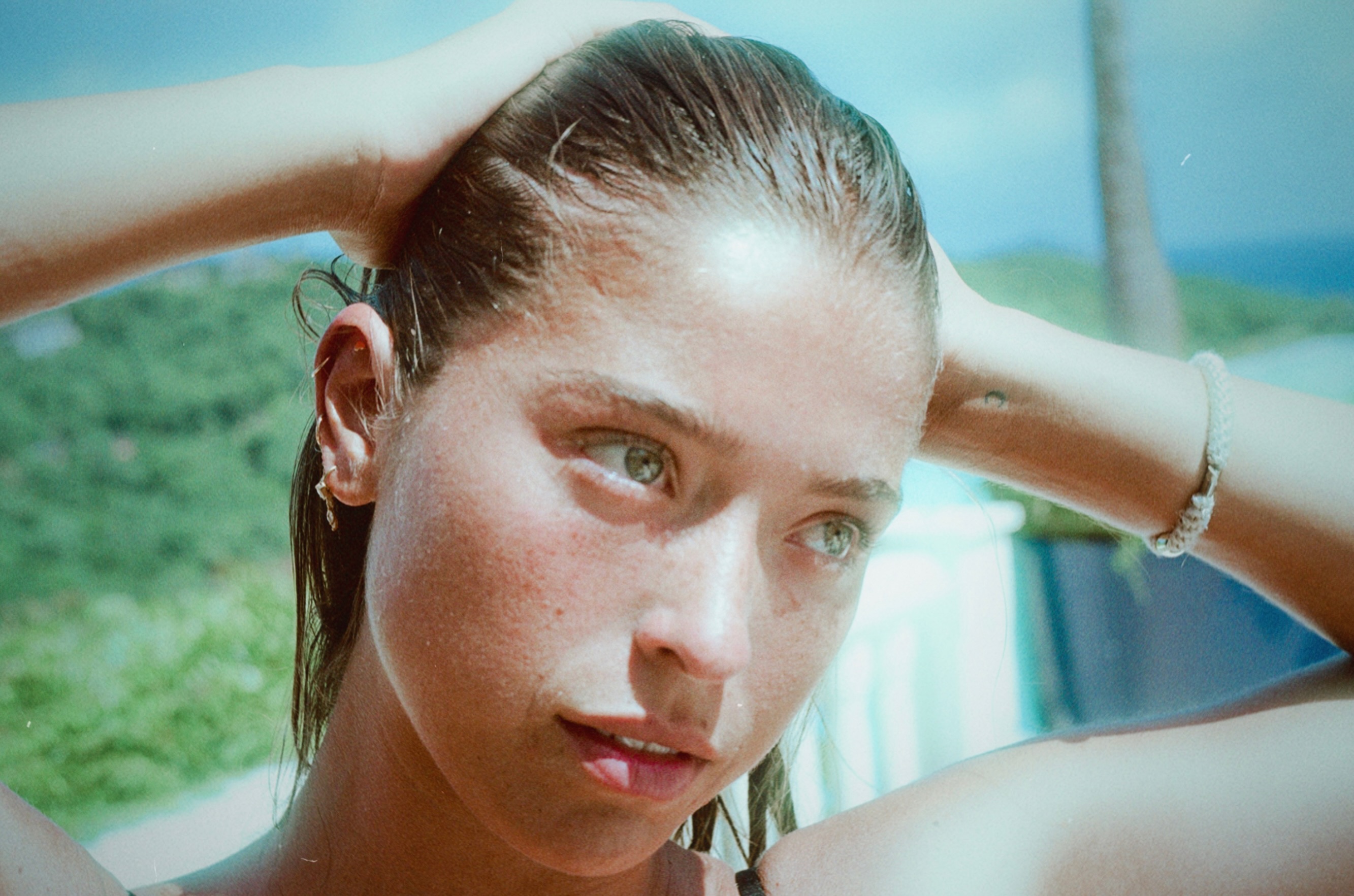 Lola Consuelos opened her 14-photo Instagram carousel with a sun-soaked close-up, posing with wet, slicked-back brunette hair and both hands swept behind her head. | Source: Instagram/theyoungestyung