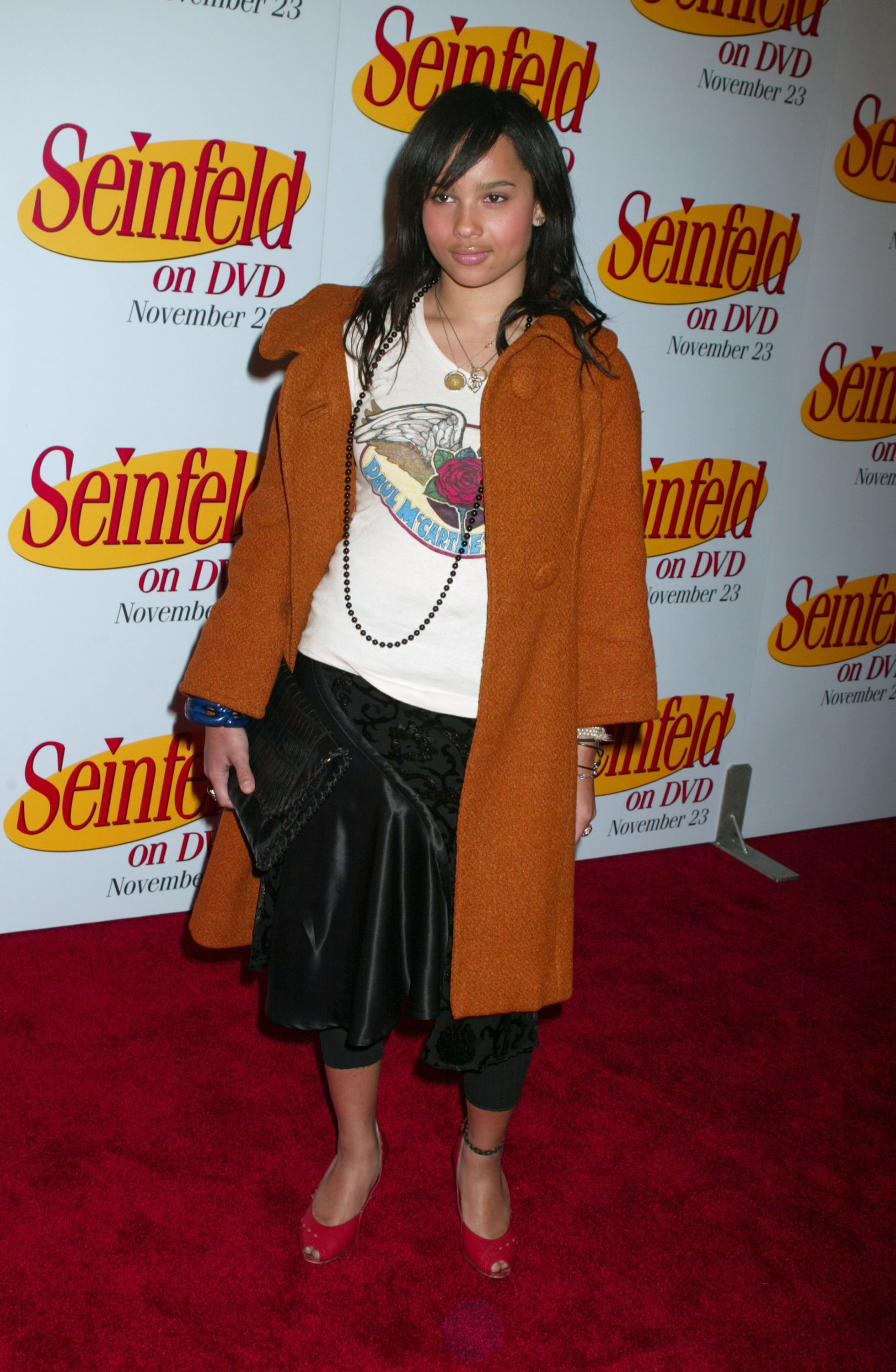 Zoë Kravitz attended the "Seinfeld" DVD Release Party at Rockefeller Plaza in New York City on November 17. She wore a rust-orange coat over a Paul McCartney graphic tee, paired with a black satin skirt, cropped leggings, and red open-toe heels. She finished the look with a long black beaded necklace and a black fringed clutch.