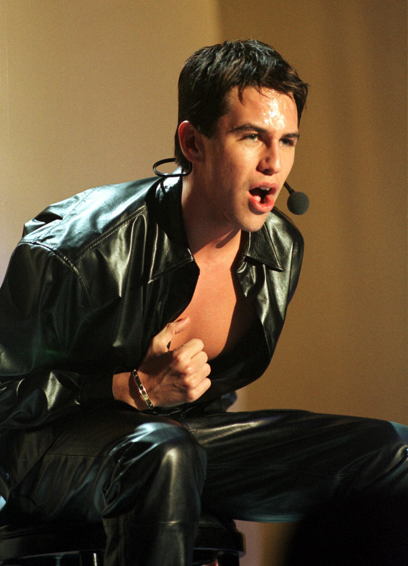 The pop singer, dressed in a black leather outfit with the top unbuttoned to reveal his chest, performs with passion at the Childline Concert in Dublin’s Point Theatre. He strikes a blend of confidence and raw emotion on stage.