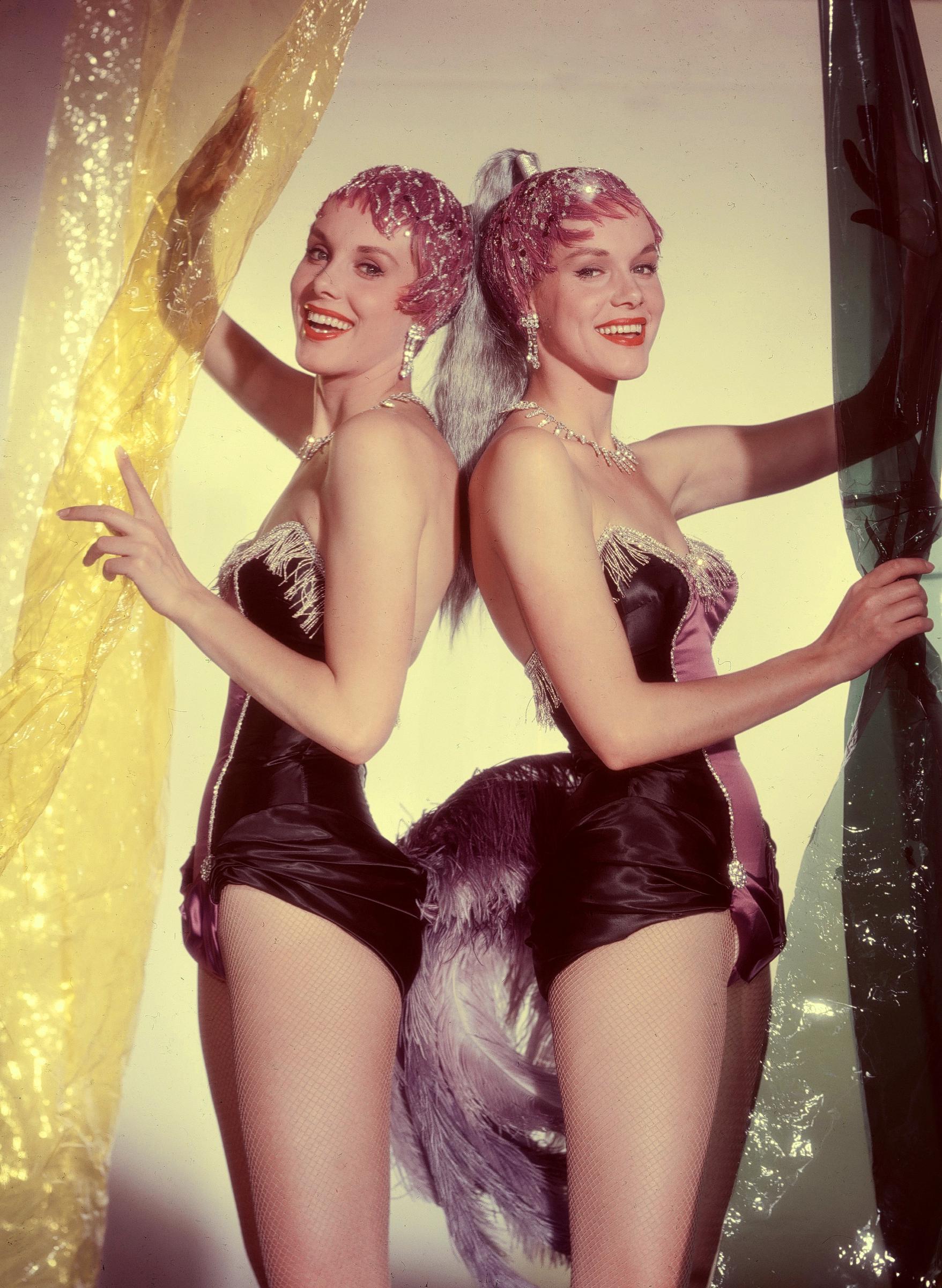 Alice and Ellen Kessler posing in showgirl aesthetic costumes in 1959. | Source: Getty Images