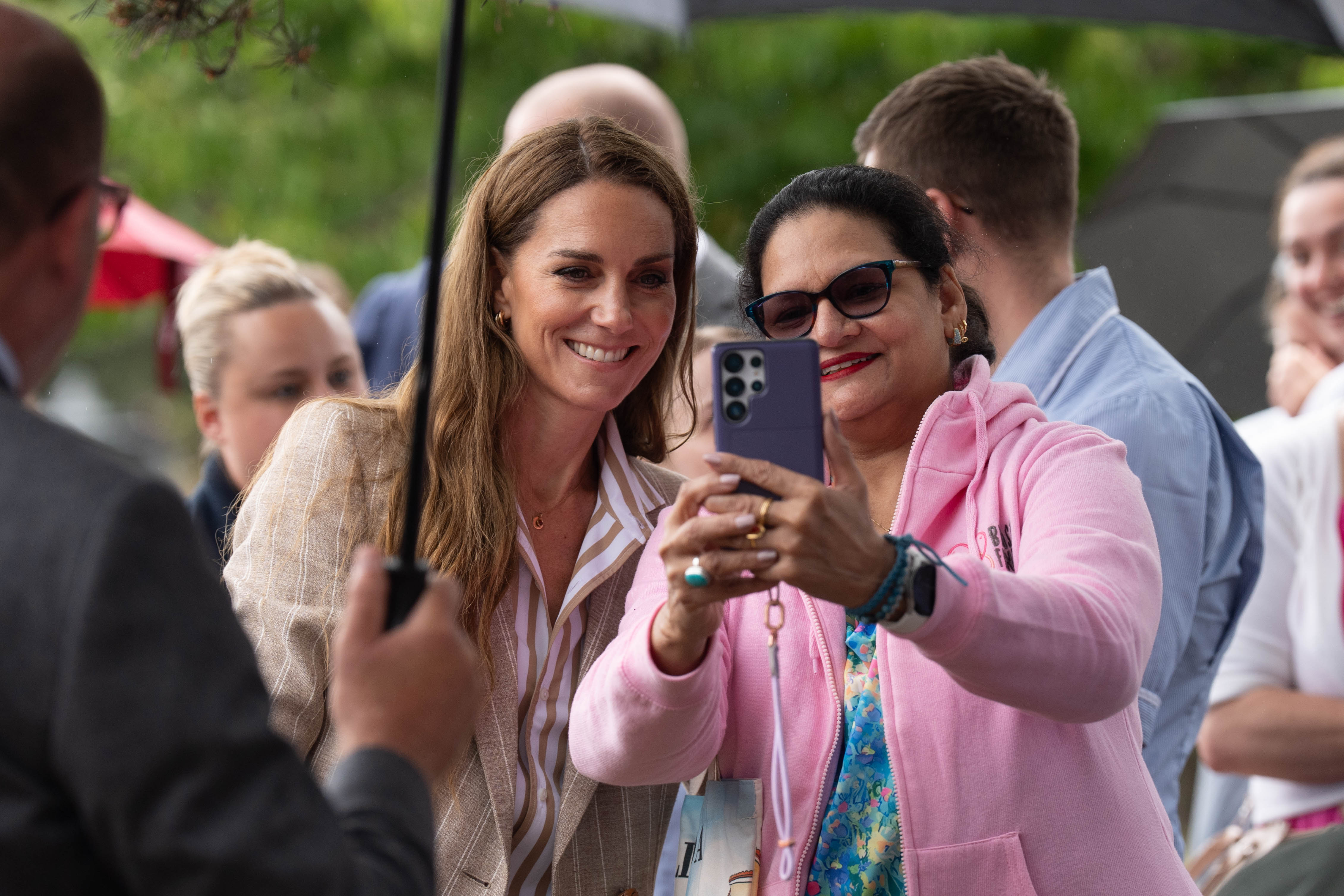 Princess Catherine shares a cheerful selfie moment with a well-wisher. Despite the rain, her gracious energy uplifted those gathered outdoors to meet her.
