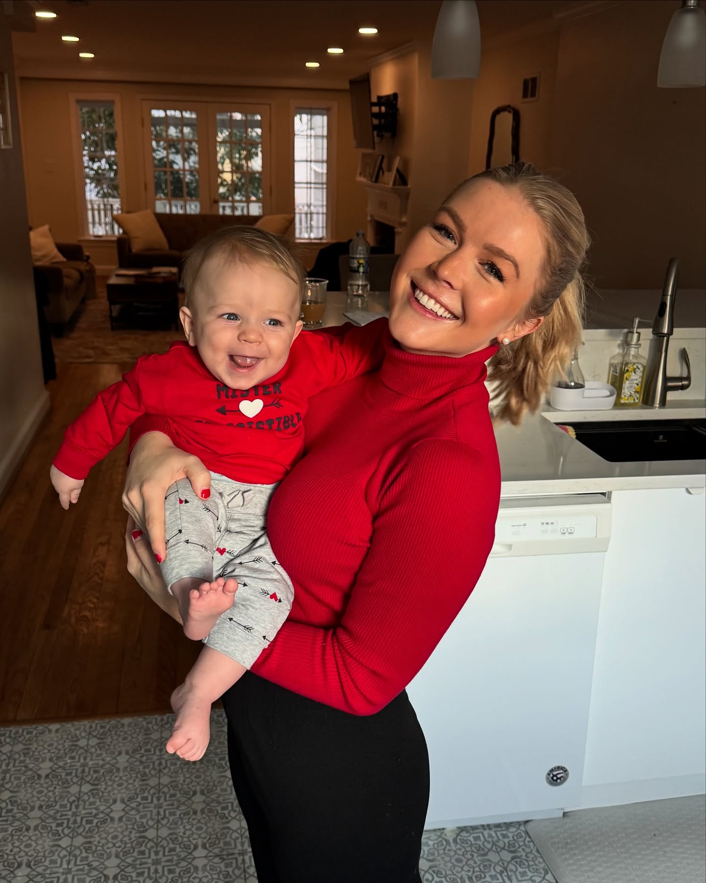 The polished white kitchen also serves as an everyday family space, not merely a glossy backdrop. Leavitt's photo with baby Niko reveals the combination of white cabinetry and darker fixtures that gives the room its crisp, modern contrast. | Source: Instagram/karolineleavitt