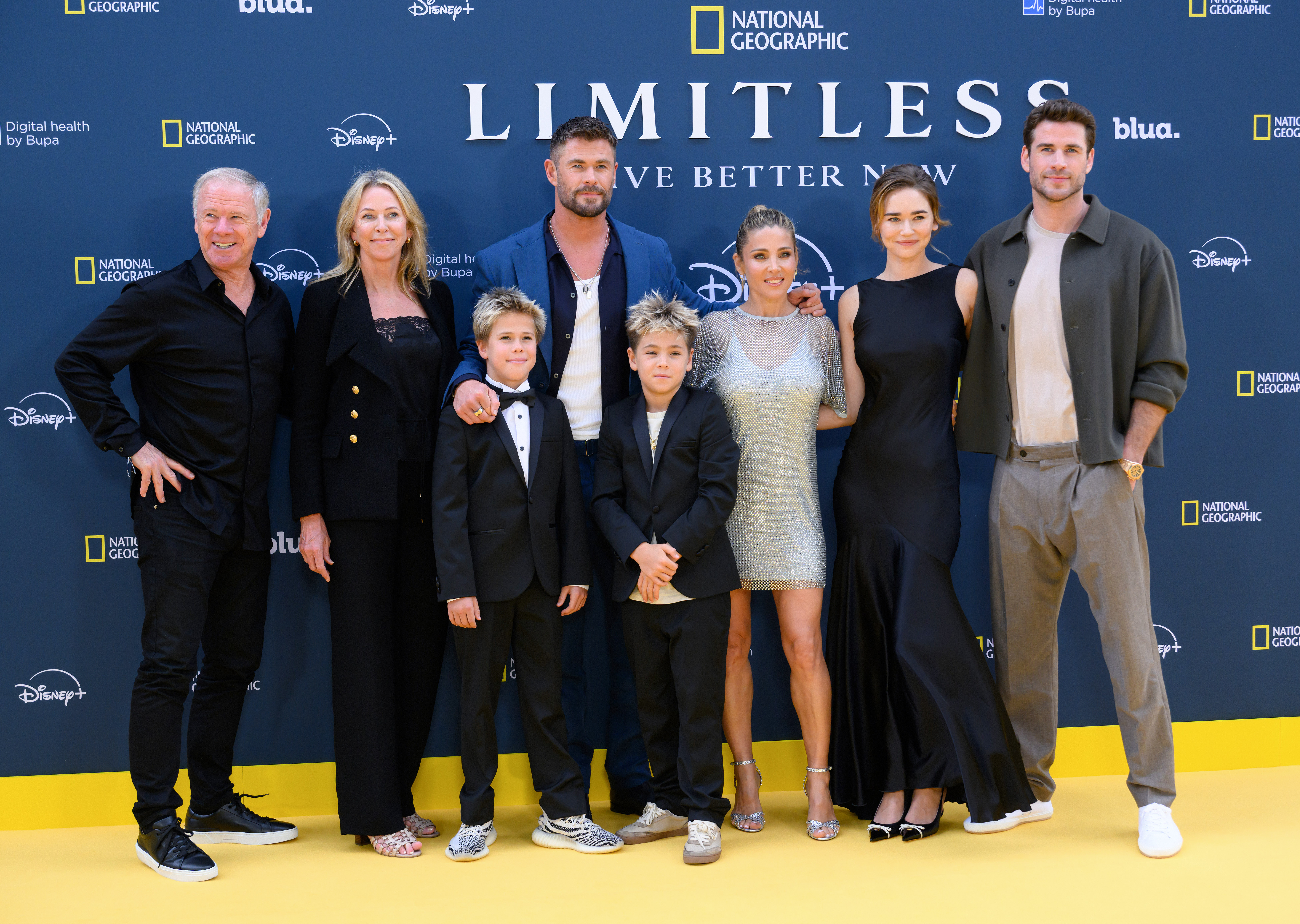 Chris Hemsworth poses with his extended family at the UK premiere of "Limitless: Live Better Now" on July 17, 2025, in London. The photo features his parents, Craig and Leonie Hemsworth, his twin sons Tristan and Sasha, wife Elsa Pataky, brother Liam Hemsworth, and Liam's partner Gabriella Brooks. The family coordinated in black and neutral tones, with Elsa standing out in a shimmering silver mini dress.