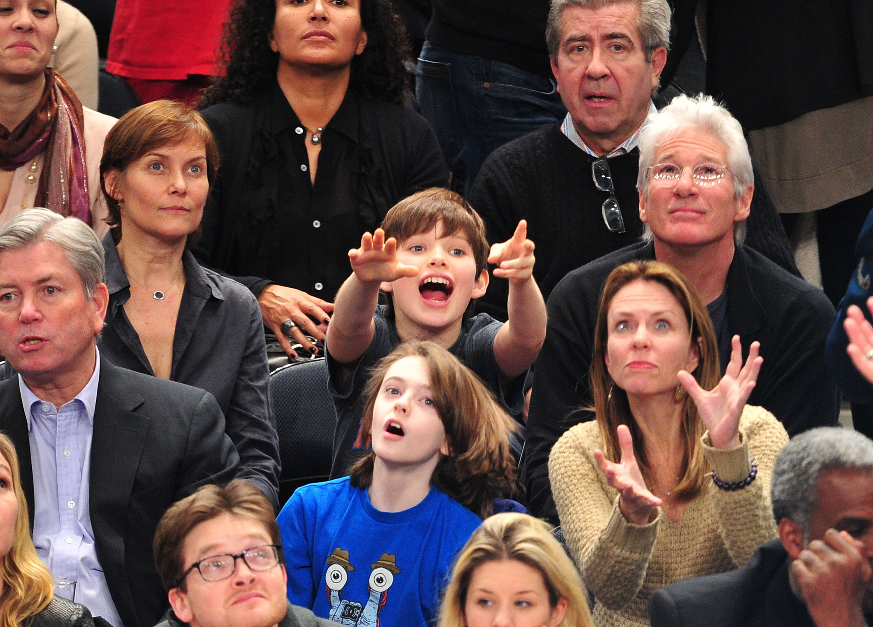With excitement in his eyes, Homer Gere gestures toward the court as he watches the New York Knicks take on the Chicago Bulls at Madison Square Garden in New York City, seated beside his parents, Carey Lowell and Richard Gere.