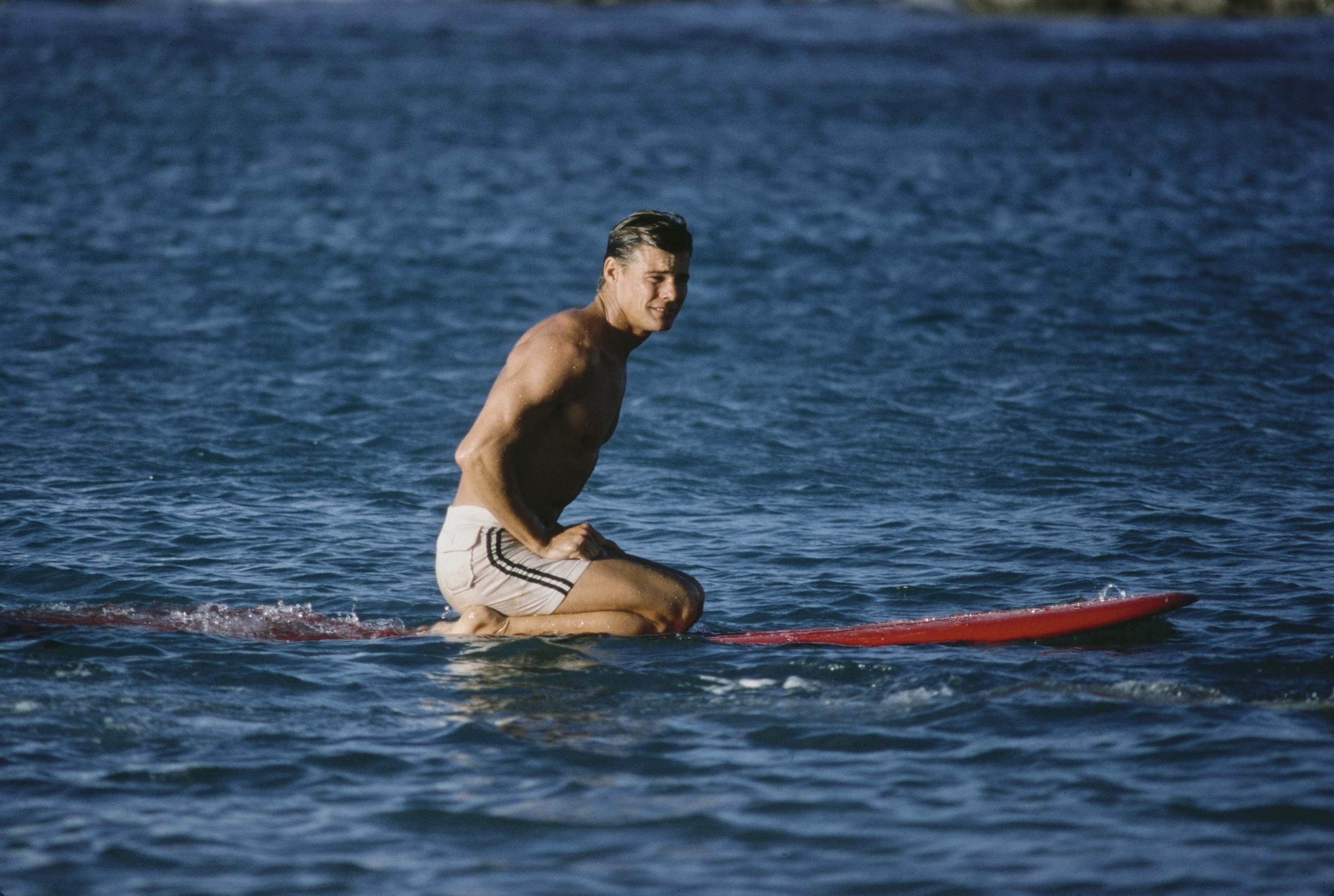 Jan-Michael Vincent kneeling on a surfboard while filming "Big Wednesday" at Sunset Beach in O'ahu, Hawaii, in September 1977. | Source: Getty Images