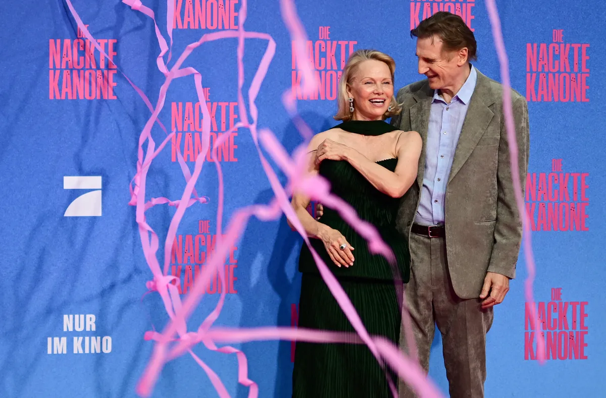 Pamela Anderson and Liam Neeson share a laugh with one another on the red carpet premiere of "The Naked Gun" on July 24, 2025 in Berlin, Germany.