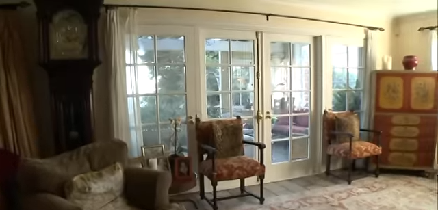 Classic grid-pane French doors let in natural light and lead directly out to the property's lush backyard patio. | Source: YouTube/@Biography