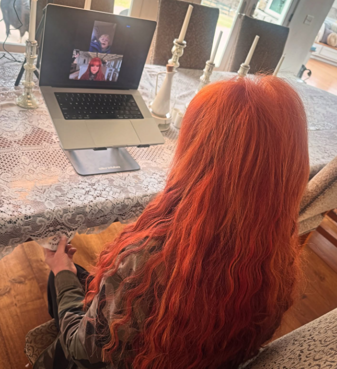 Wynonna sits at a dining table with a laptop propped in front of her during a video conversation. Tall candlesticks and a patterned tablecloth frame the scene, showing another way she uses the space beyond meals. | Source: Instagram/wynonnajudd