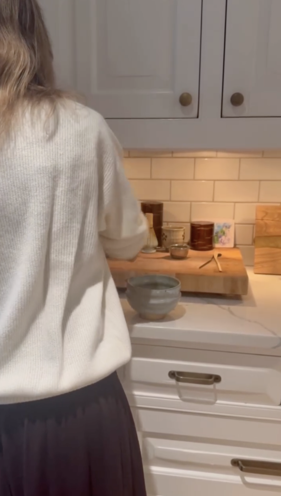 Alejandra Silva stands at a kitchen counter inside the family's Spain home, offering a glimpse of the bright space with white cabinetry, subway-tile backsplashes, and warm under-cabinet lighting. | Source: Instagram/alejandragere