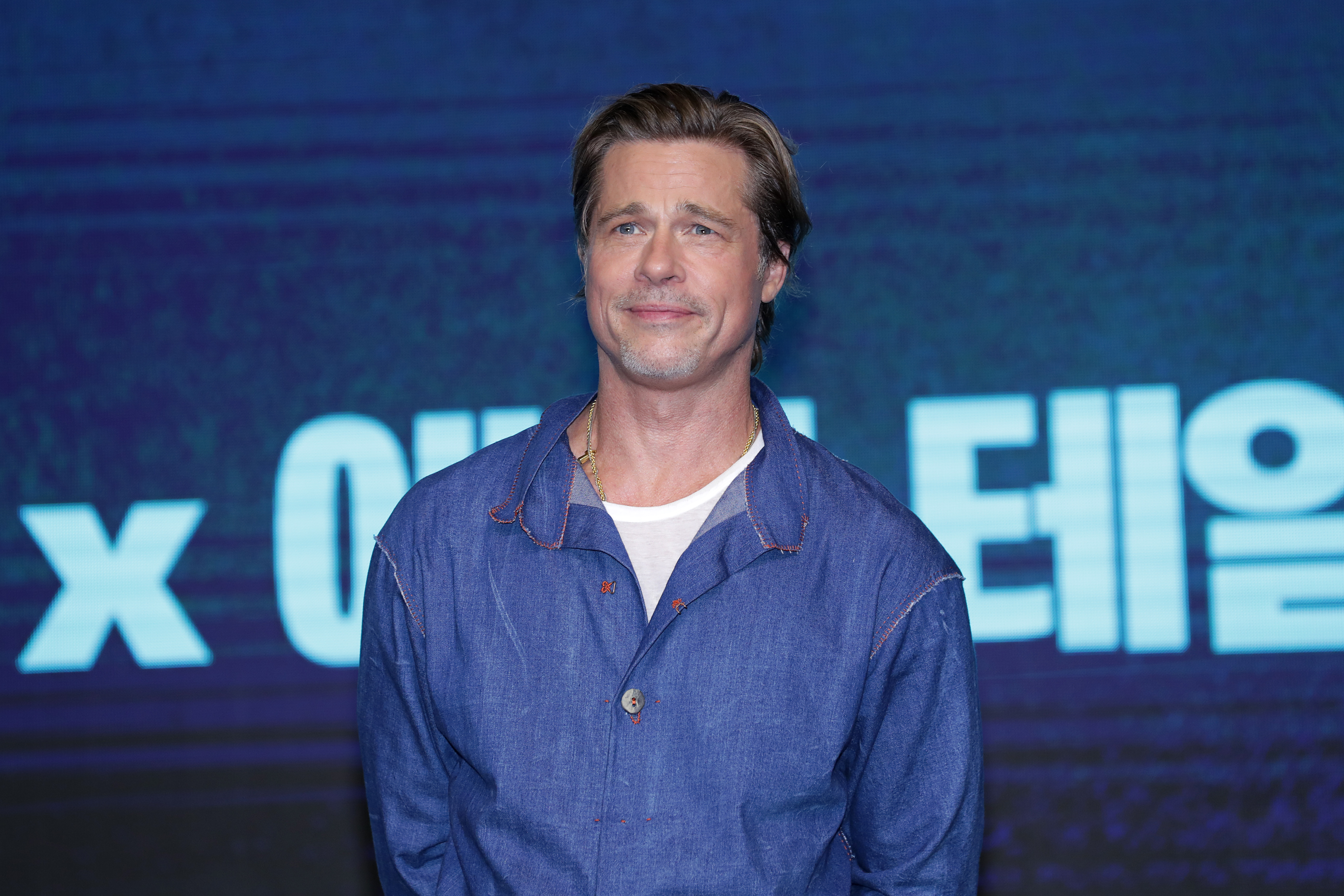 Brad Pitt at a press conference in Seoul, standing against a branded backdrop during a film promotion | Source: Getty Images