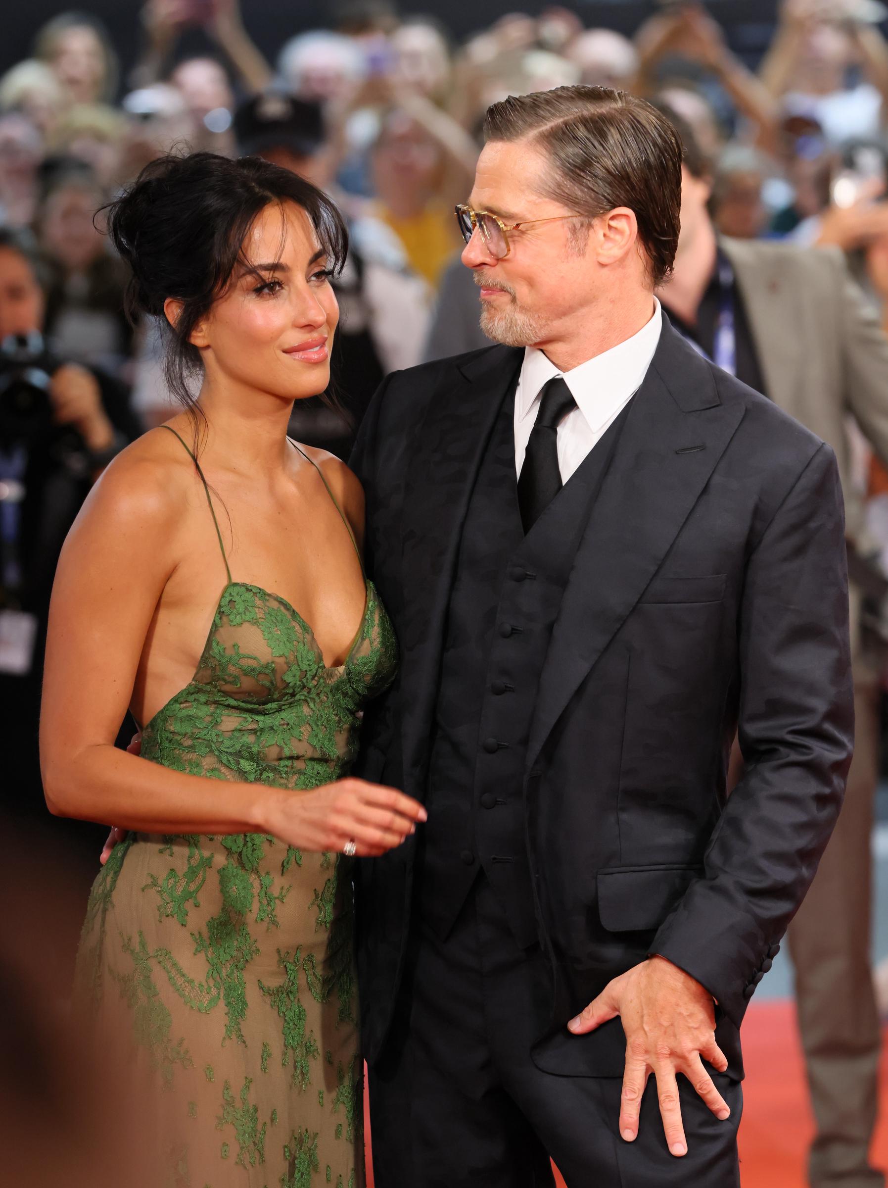 De Ramon faced the cameras while Pitt looked toward her in another close frame from the screening. The shot offered a clearer view of their contrasting styling, from her loose updo and green lace to his slicked-back hair and black suit.