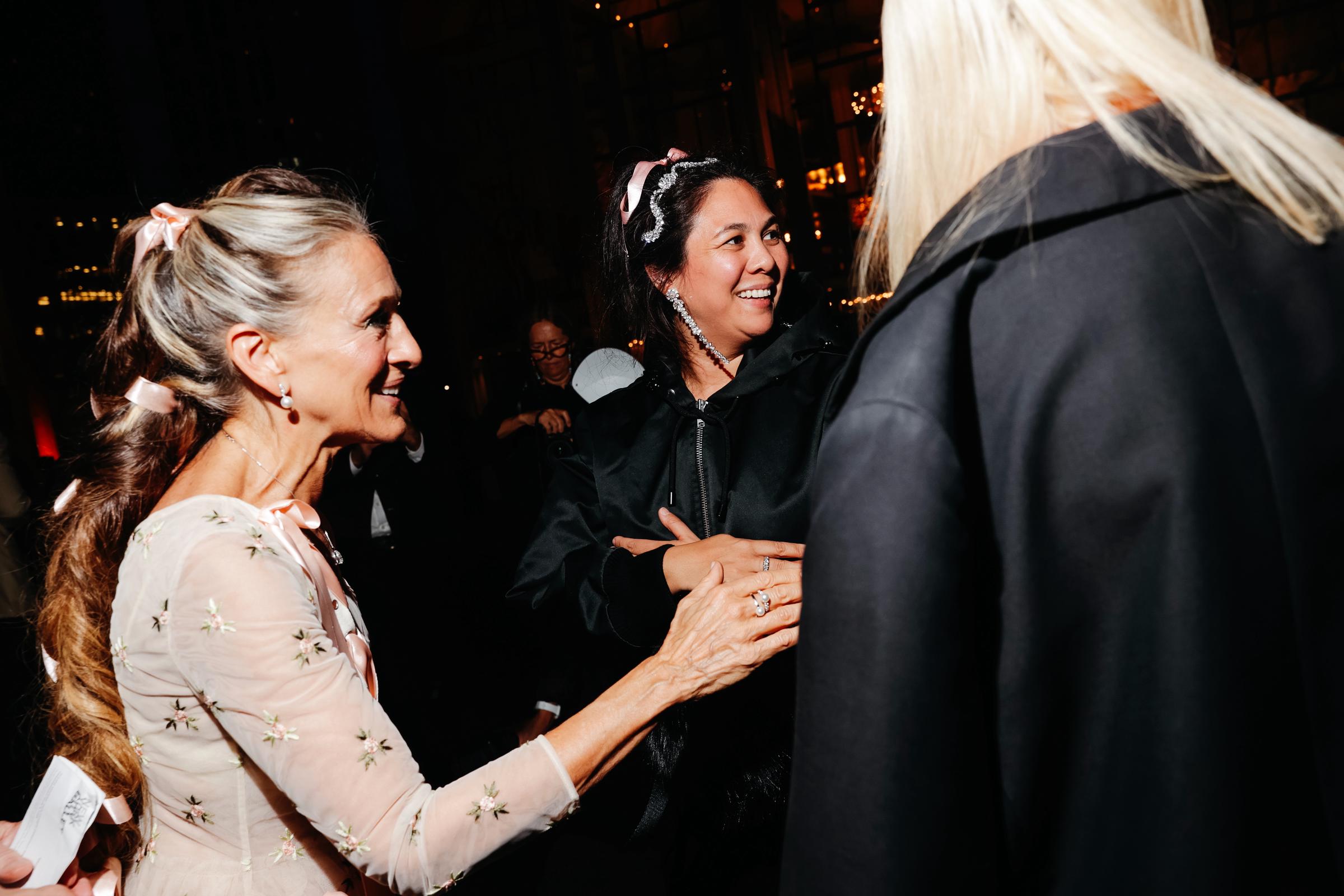 Sarah Jessica Parker chats with designer Simone Rocha at the New York City Ballet Fall Fashion Gala on October 1, 2026. Her long ponytail, tied with pink ribbons, reveals silver strands near her hairline. | Source: Getty Images
