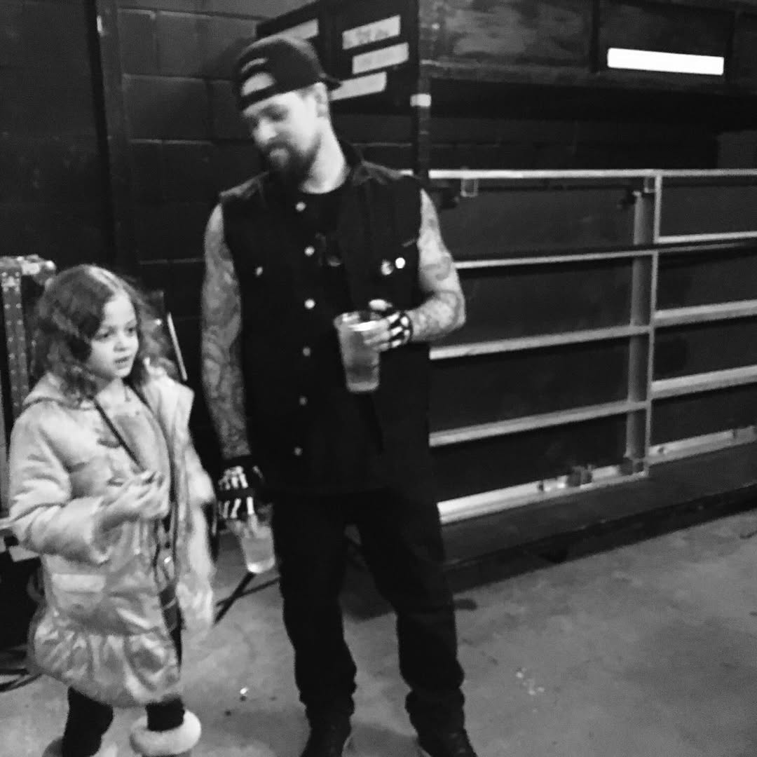 Joel Madden stands beside Harlow Winter Kate Madden in a black-and-white backstage-style photo. Holding drinks and dressed casually, father and daughter appear mid-conversation in a candid childhood moment. | Source: Instagram/nicolerichie and joelmadden