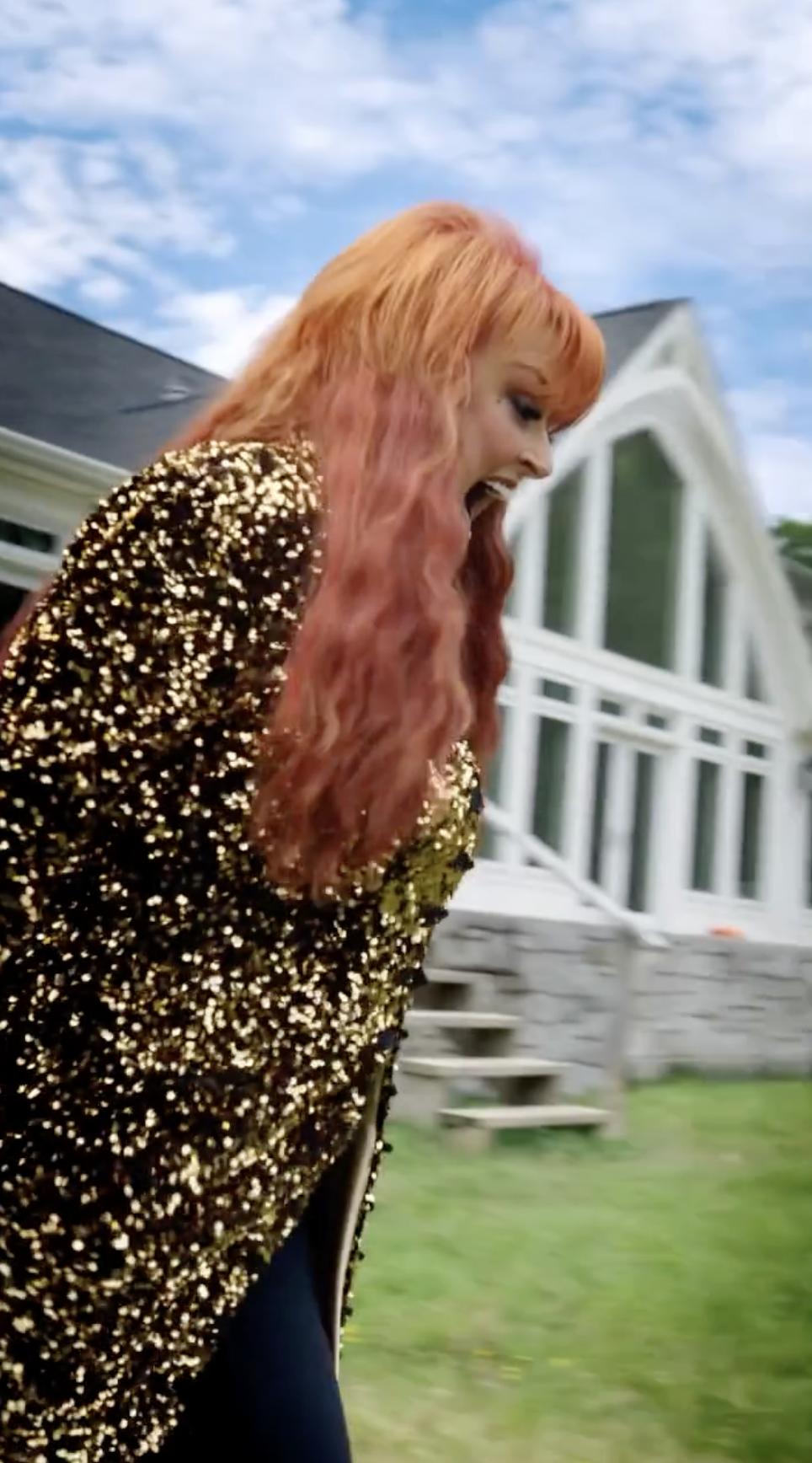Wynonna appears outside the house, with a steep roofline, large windows, and steps visible behind her. The photograph gives readers another ground-level view of the residence before the story turns to everyday life on the ranch. | Source: Getty Images
