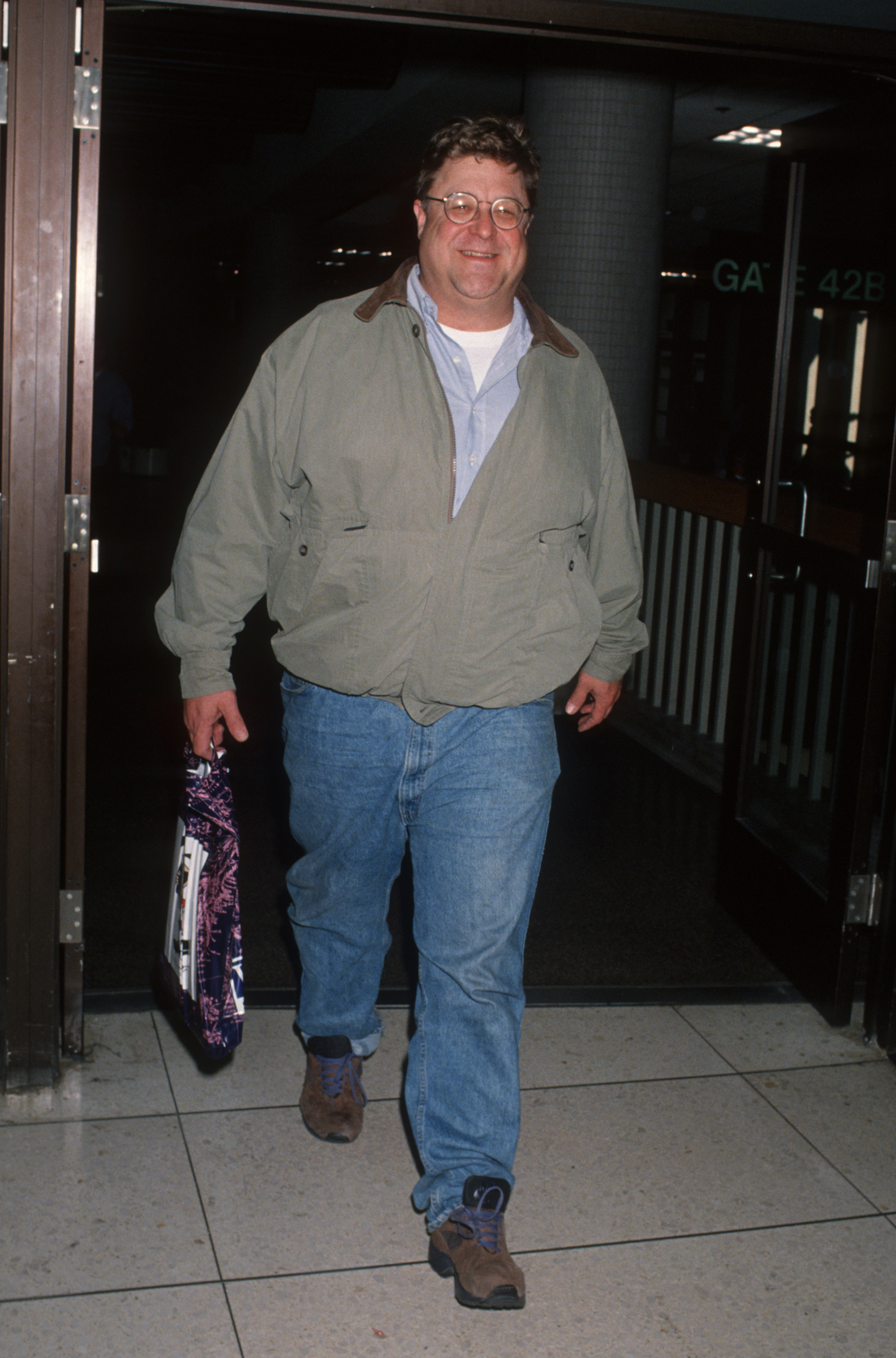 Goodman was photographed at Los Angeles International Airport wearing jeans, a light jacket and glasses as he walked through the terminal. The casual full-length image shows his former physique clearly, providing a visual point of comparison with the much leaner appearance seen later in his life.