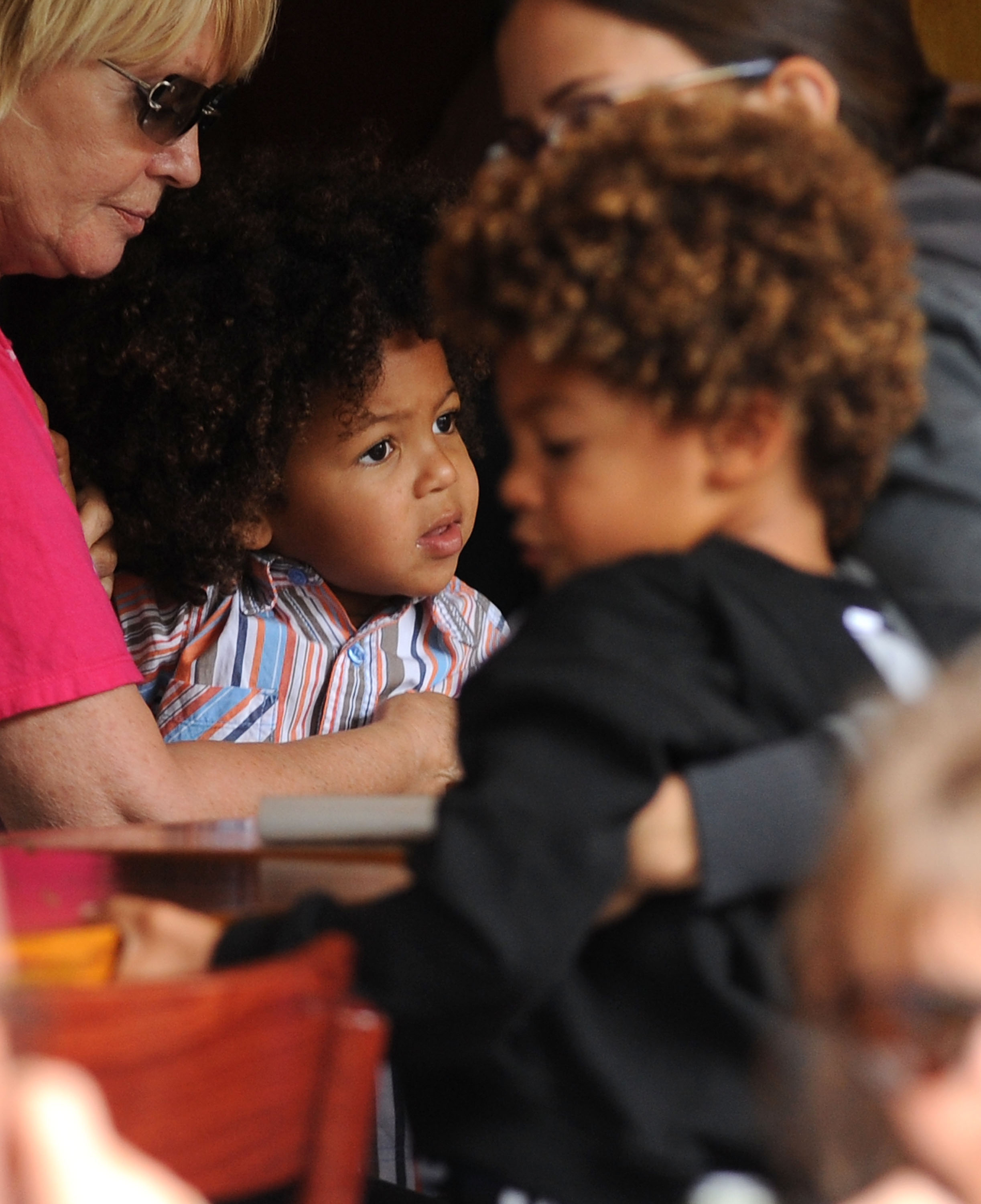 Heidi Klum and Seal's sons, Johan and Henry Samuel, are seated around a table as they eat lunch. The boys are dressed in outfits that reflect a comfortable, everyday look suitable for a relaxed family outing.