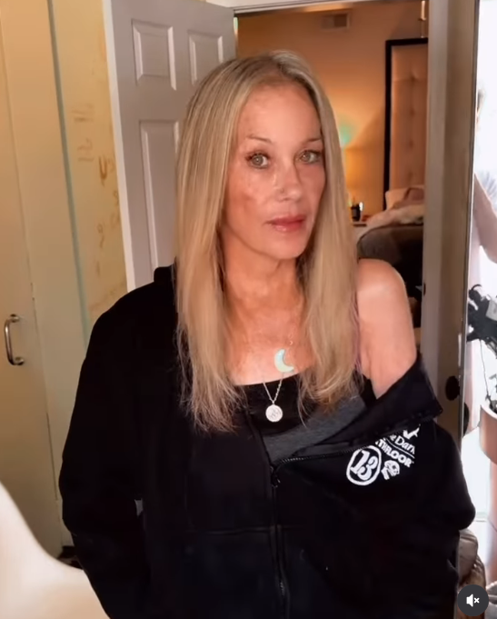 Christina Applegate paused to look straight into the camera lens with a serene, glowing gaze during a personal video shared on September 21, 2026. Her straight blonde strands framed a soft, makeup-free face accented by layered crescent and medallion jewelry that brightened her dark casual zip-up. | Source: Instagram/christinaapplegate