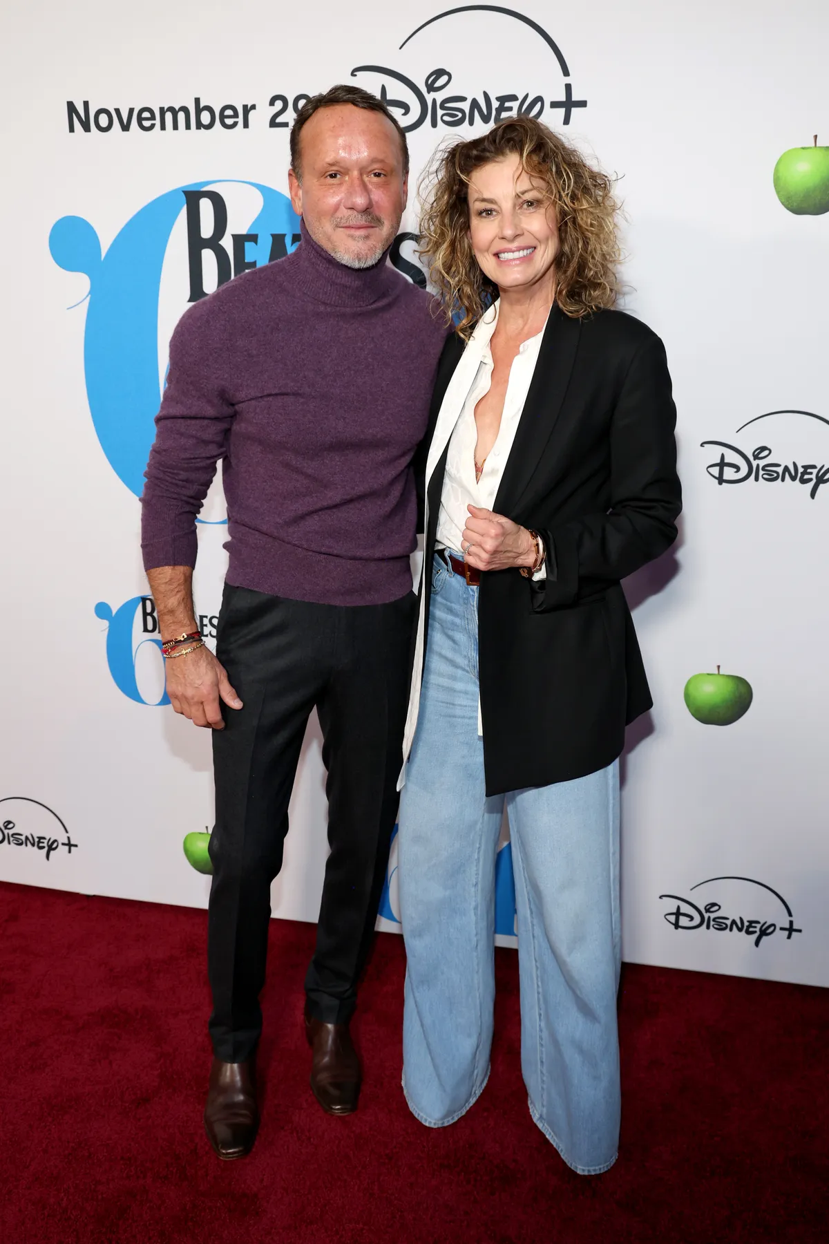 Faith Hill goes retro-chic in a boxy blazer and wide-leg jeans while Tim McGraw opts for a rich plum turtleneck at the "Beatles '64" premiere. Their easy smiles and relaxed stance bring a fresh energy to the red carpet.