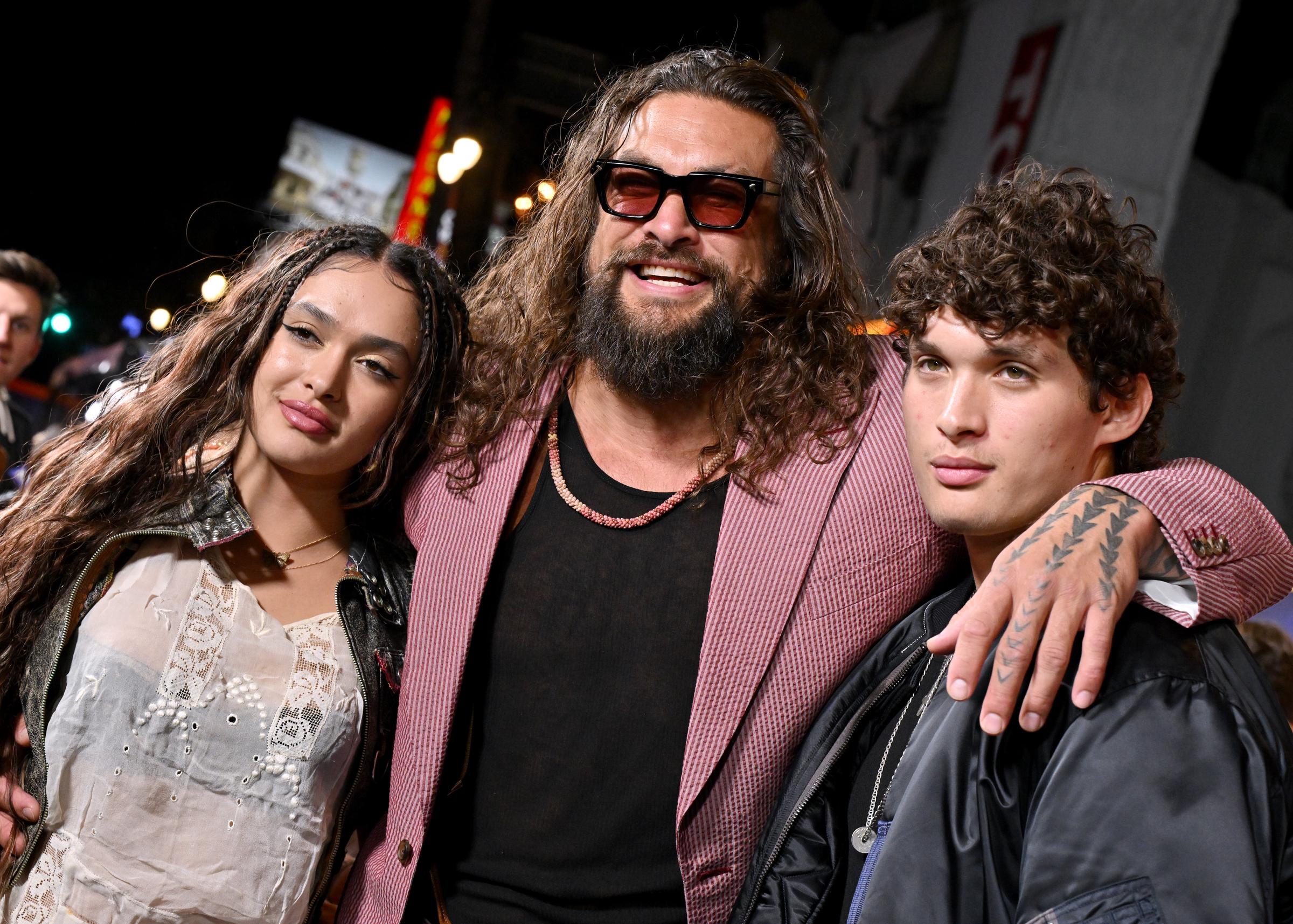 Jason Momoa pulls daughter Lola Iolani Momoa and son Nakoa-Wolf Momoa close for an intimate family portrait on the arrivals carpet at the TCL Chinese Theatre during the premiere of "Street Fighter". The actor beams proudly with an arm wrapped around each of them, showing off his wrist and hand tattoos, while Lola showcases delicate face-framing accent braids and Nakoa-Wolf matches his father's relaxed charisma. | Source: Getty Images