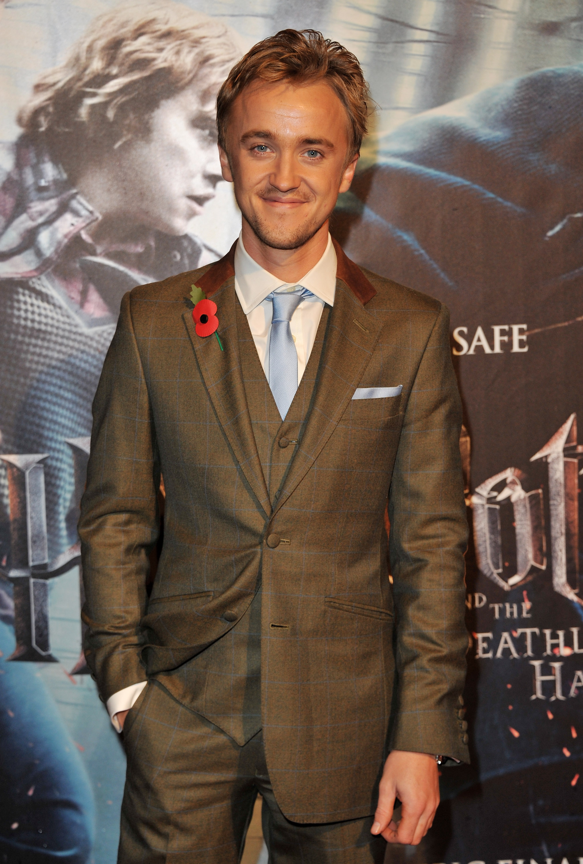Tom Felton steps out for the "Harry Potter and The Deathly Hallows" premiere in a sharply tailored suit, looking every bit the polished opposite of his on-screen persona. With a soft smile and a poppy pinned to his lapel, he carries a quiet confidence beneath the whirlwind of excitement around him. Framed against the film's dramatic backdrop, he stands poised at the dawn of Harry Potter's final chapter.