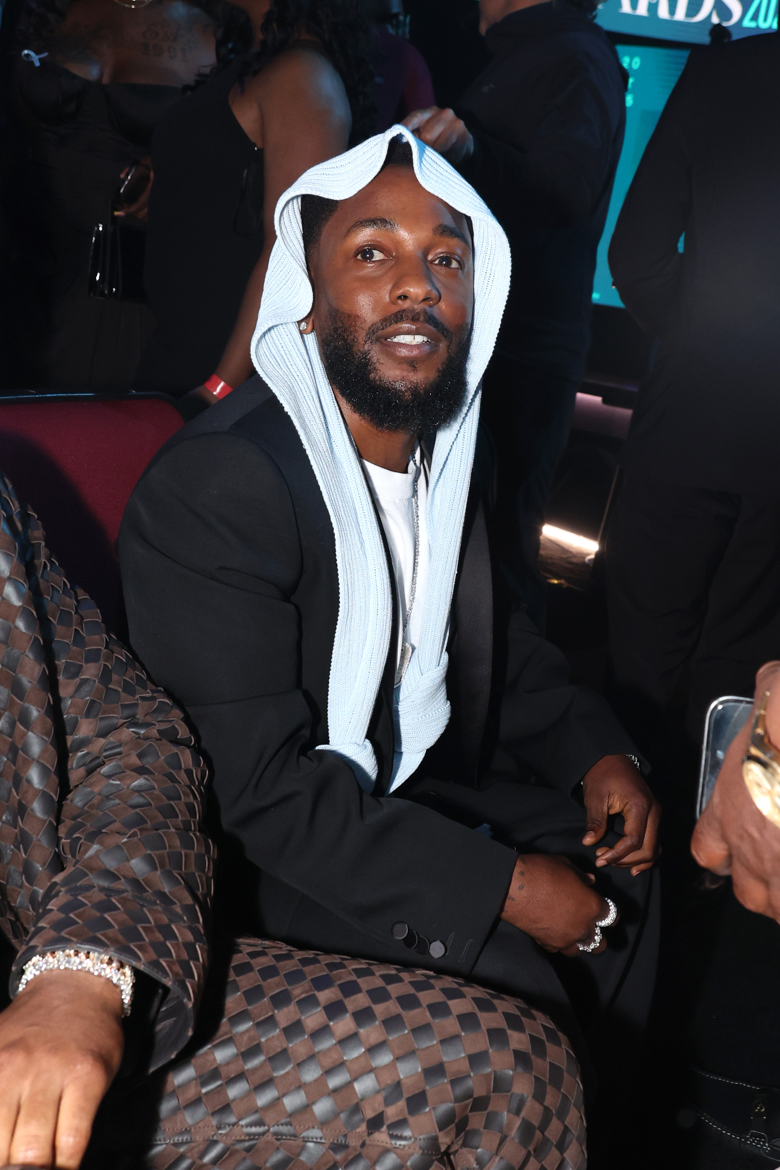 Seated in the audience during the 2025 BET Awards, Kendrick Lamar flashes a relaxed smile. His head covering remained the center of online buzz as he watched the show from his spot at the Peacock Theater.