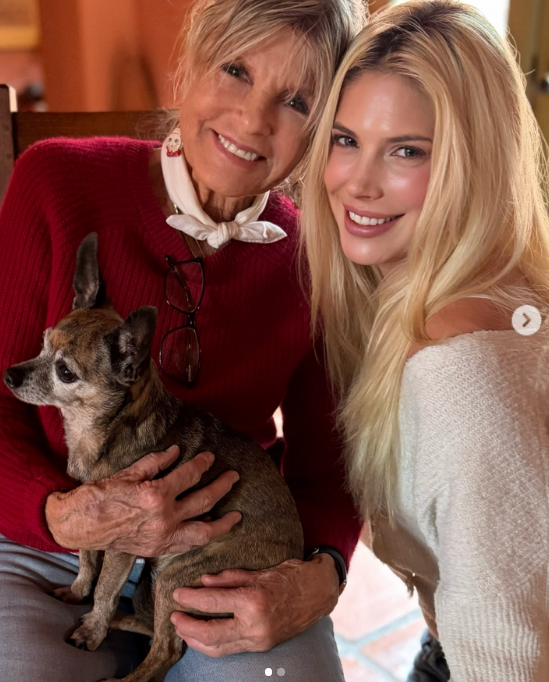 Katharine Ross and daughter Cleo Rose Elliott enjoyed a cozy family moment at home in a sweet photo shared on January 29, 2026. The veteran actress held an adorable small dog in her lap, wearing a vibrant red knit crewneck accented with a petite white neckerchief. Leaning close beside her, Cleo flashed a radiant grin in an off-the-shoulder cream knit, her sunlit blonde locks draped effortlessly over one shoulder. | Source: Instagram/cleoroseelliott