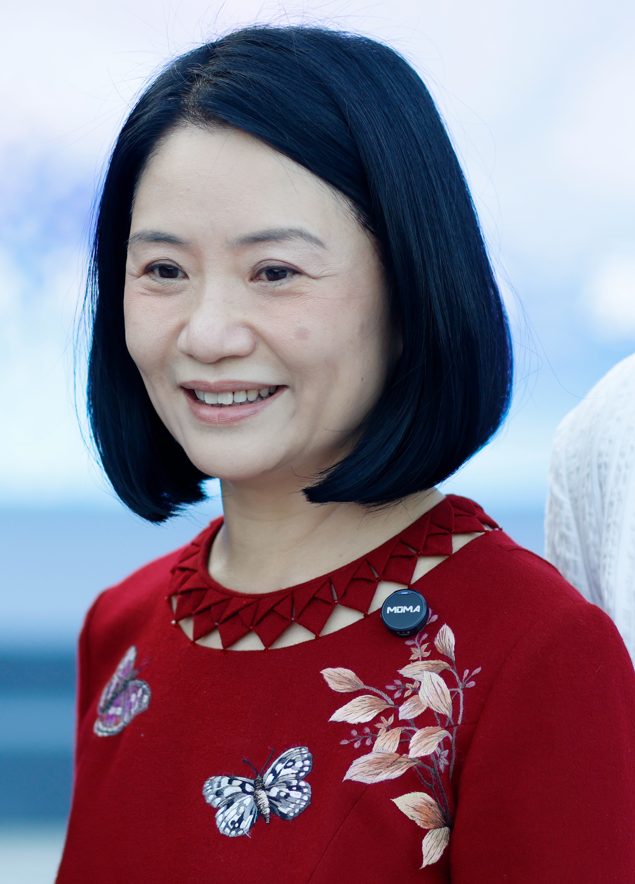 Acclaimed Chinese couturier Guo Pei smiled brightly during Beijing Fashion Week Spring/Summer 2027 on September 5, 2026, in Beijing, China. Showcasing a chic, sleek bob, the celebrated designer wore a vibrant crimson red garment featuring an intricately geometric cut-out neckline and delicate botanical embroidery adorned with fluttering butterfly motifs. | Source: Getty Images