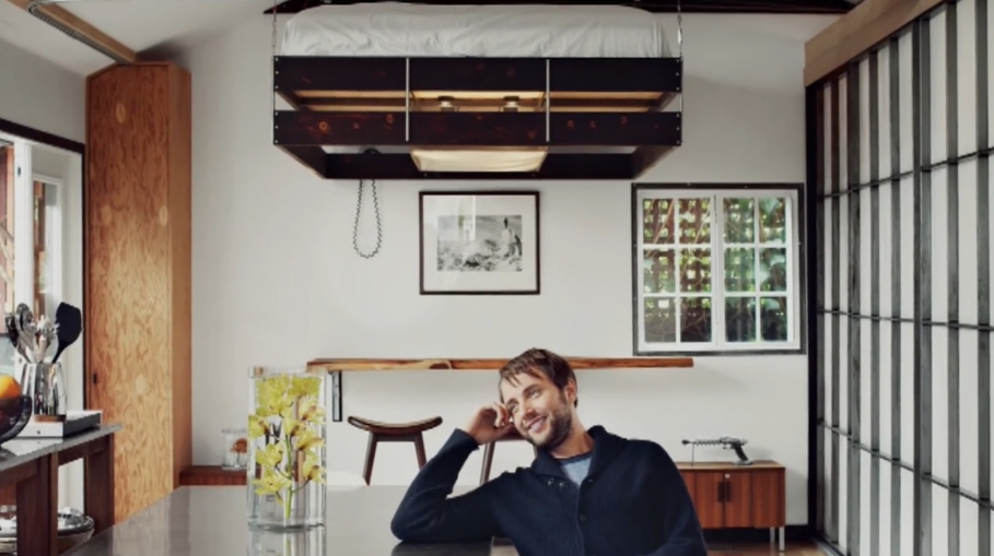 Vincent Kartheiser poses inside his thoughtfully designed 580-square-foot home, where a ceiling-mounted bed and multifunctional furnishings maximize every inch of living space. | Source: YouTube/Dwell