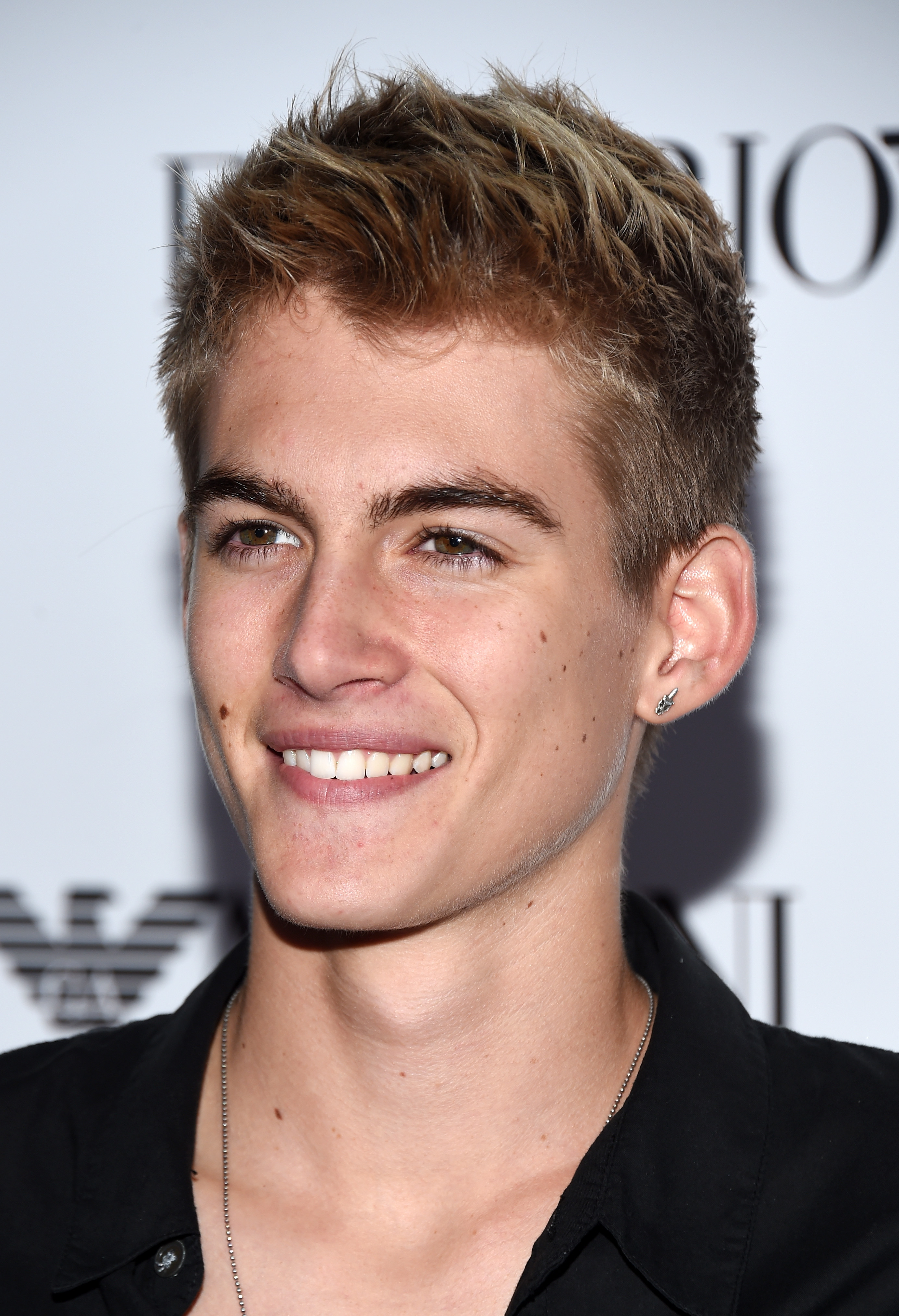 Presley Gerber gave a bright, charming smile as he arrived at Teen Vogue's 13th Annual "Young Hollywood" issue launch party on October 2, 2015, in Los Angeles, California. Sporting textured, sun-kissed blonde hair, the teen model embraced an understated look with an open-collar black shirt, a delicate silver chain, and a single stud earring. | Source: Getty Images