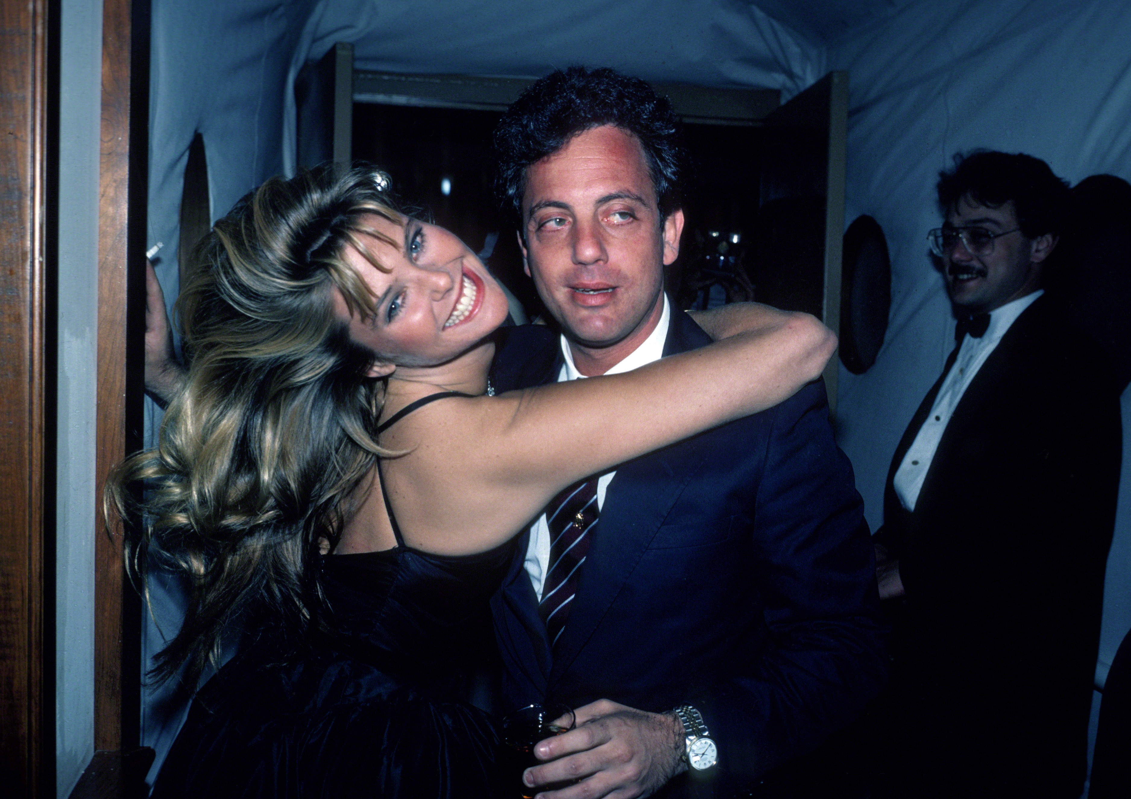 Brinkley wraps her arms around Billy Joel in New York City around 1983, the year she appeared in his "Uptown Girl" music video. Their relationship later led to marriage in 1985, adding a personal chapter to a project Brinkley never expected people would still discuss decades later. | Source: Getty Images