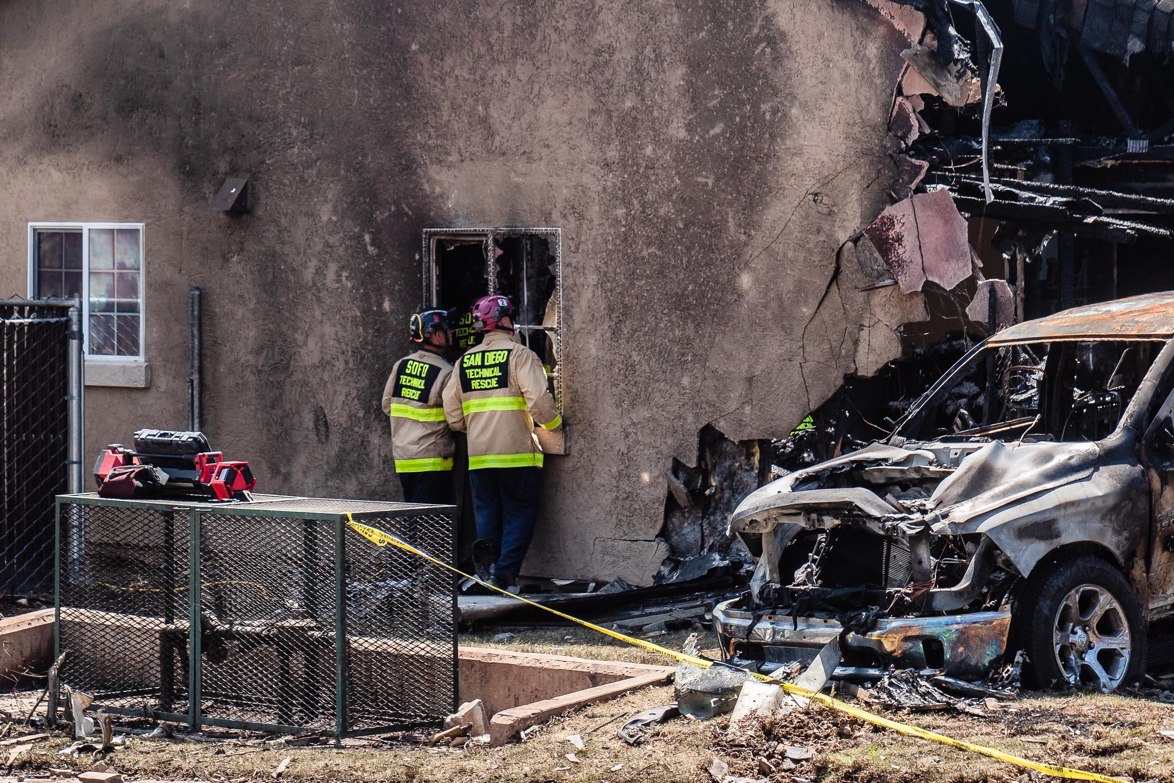 San Diego Fire-Rescue crews look through a damaged home in San Diego, California, after a small plane crashed into the neighborhood on May 22, 2025 | Source: Getty Images