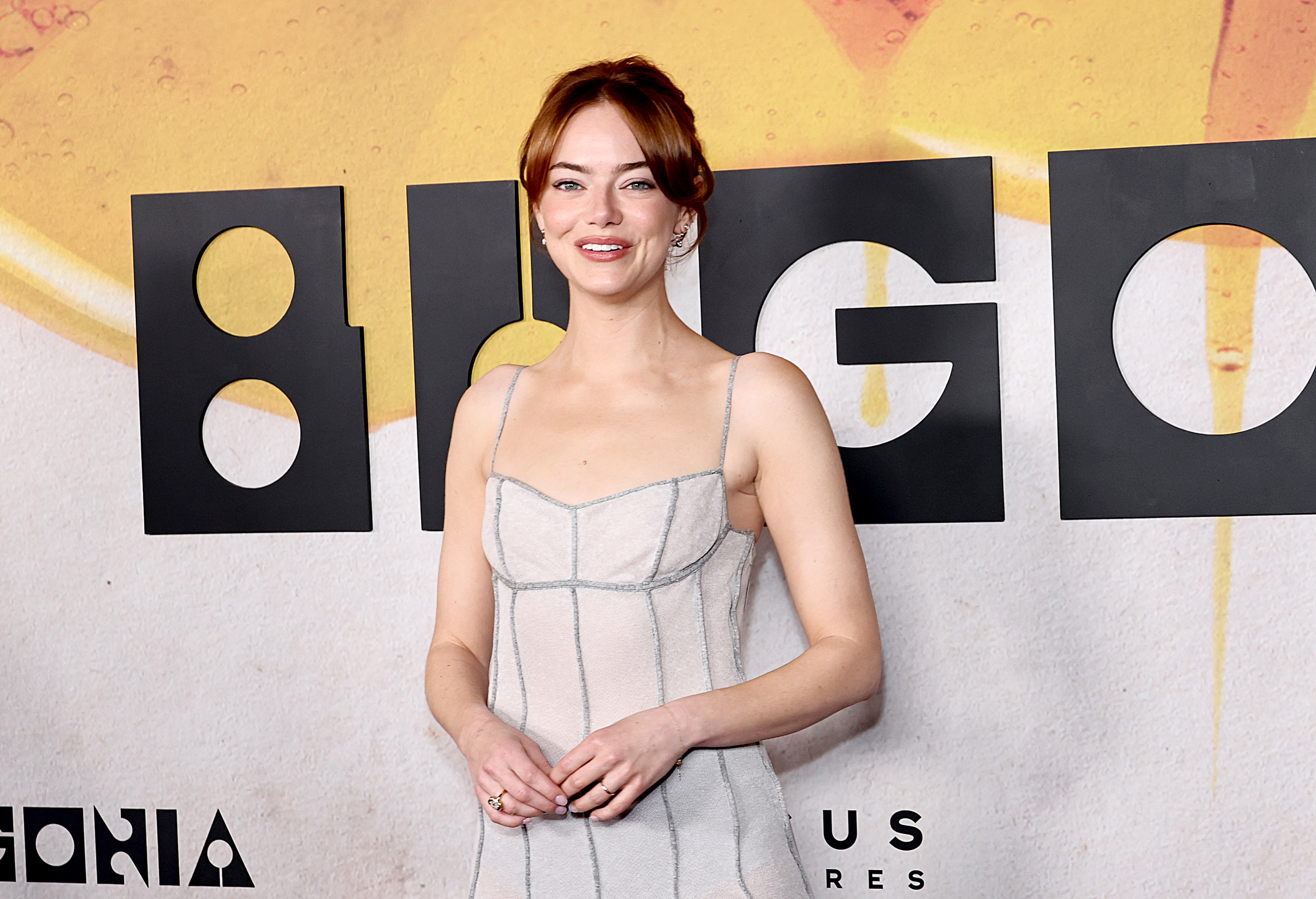 Emma Stone stands tall before the "Bugonia" backdrop, shoulders relaxed, her eyes glinting beneath the lights — a balance of modern elegance and serene self-assurance.