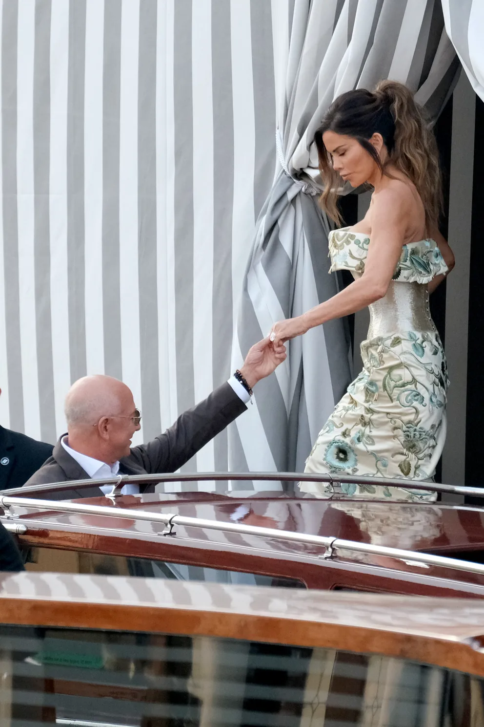 Jeff Bezos helps fiancée Lauren Sánchez, wearing a Schiaparelli couture gown, board a water taxi in Venice on June 26, 2025. | Source: Getty Images
