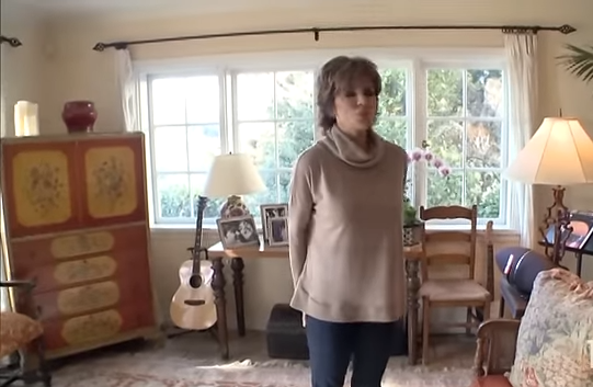 The reality star showcases the room's traditional aesthetic, complete with an acoustic guitar resting in the corner. | Source: YouTube/@Biography