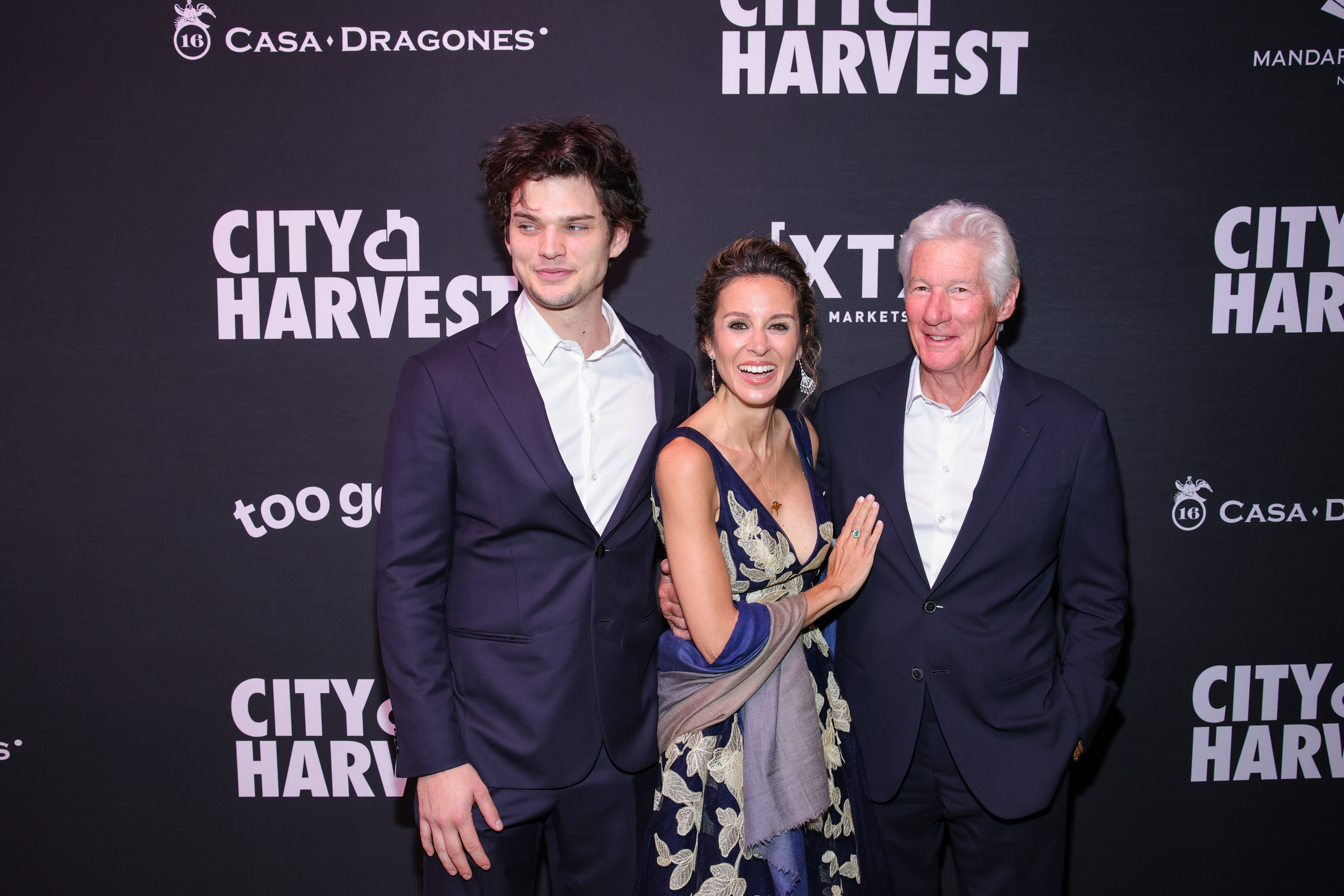 Homer Gere stands tall beside Alejandra and Richard Gere at the City Harvest Gala in New York City. With arms gently linked and warm smiles, the trio strikes a poised yet relaxed pose on the step-and-repeat.
