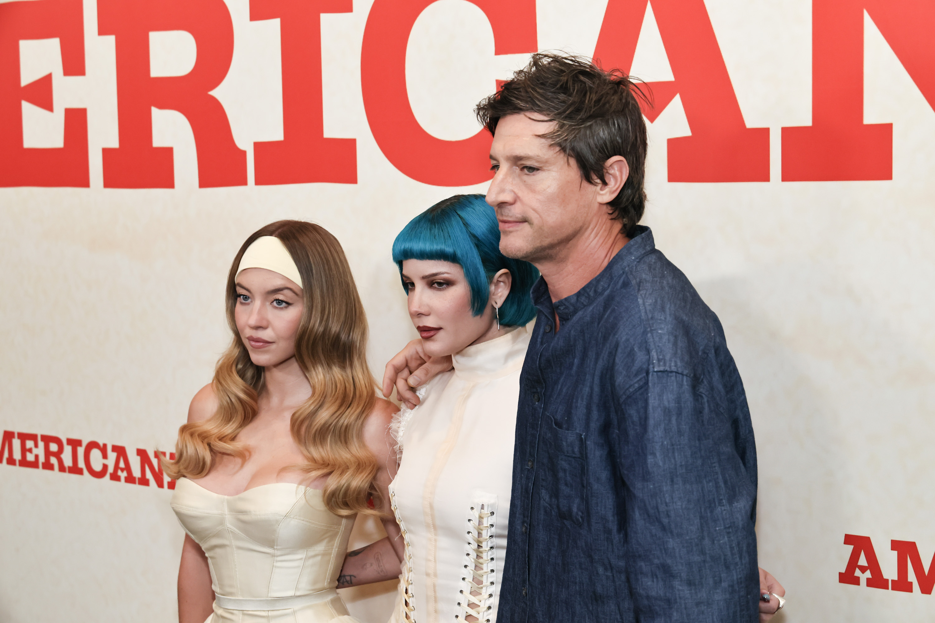 In this medium shot, Sydney Sweeney stands next to co-stars Halsey and Simon Rex, posing together at the event as all three smile for the camera.