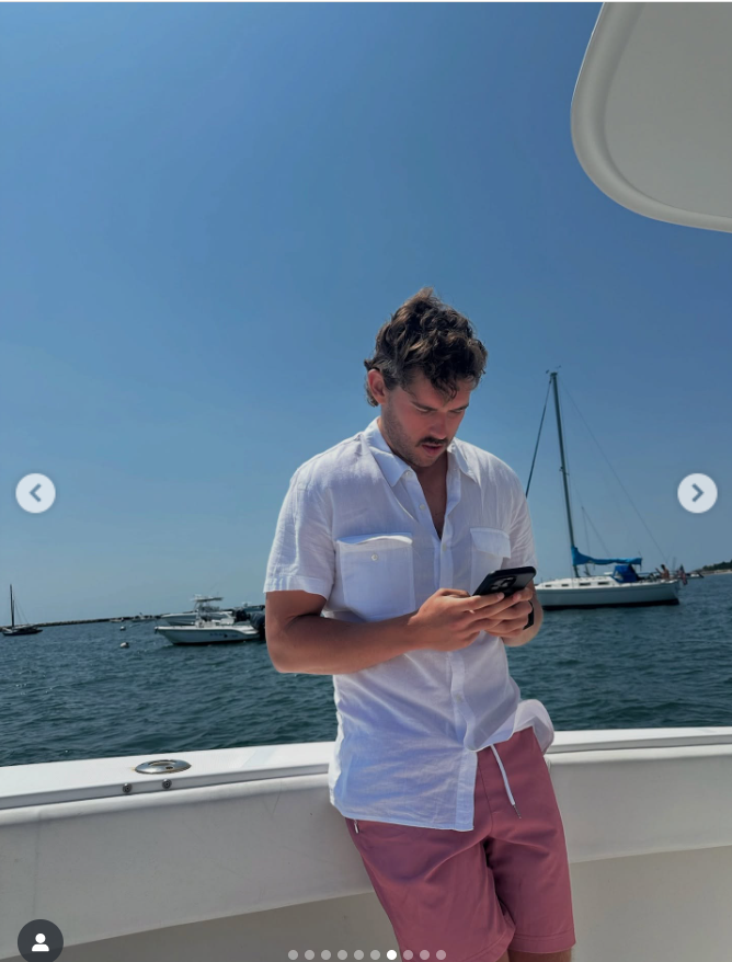 Christopher Schwarzenegger stands on a boat, looking at his phone, from a post dated August 23, 2025 | Source: Instagram/katherineschwarzenegger