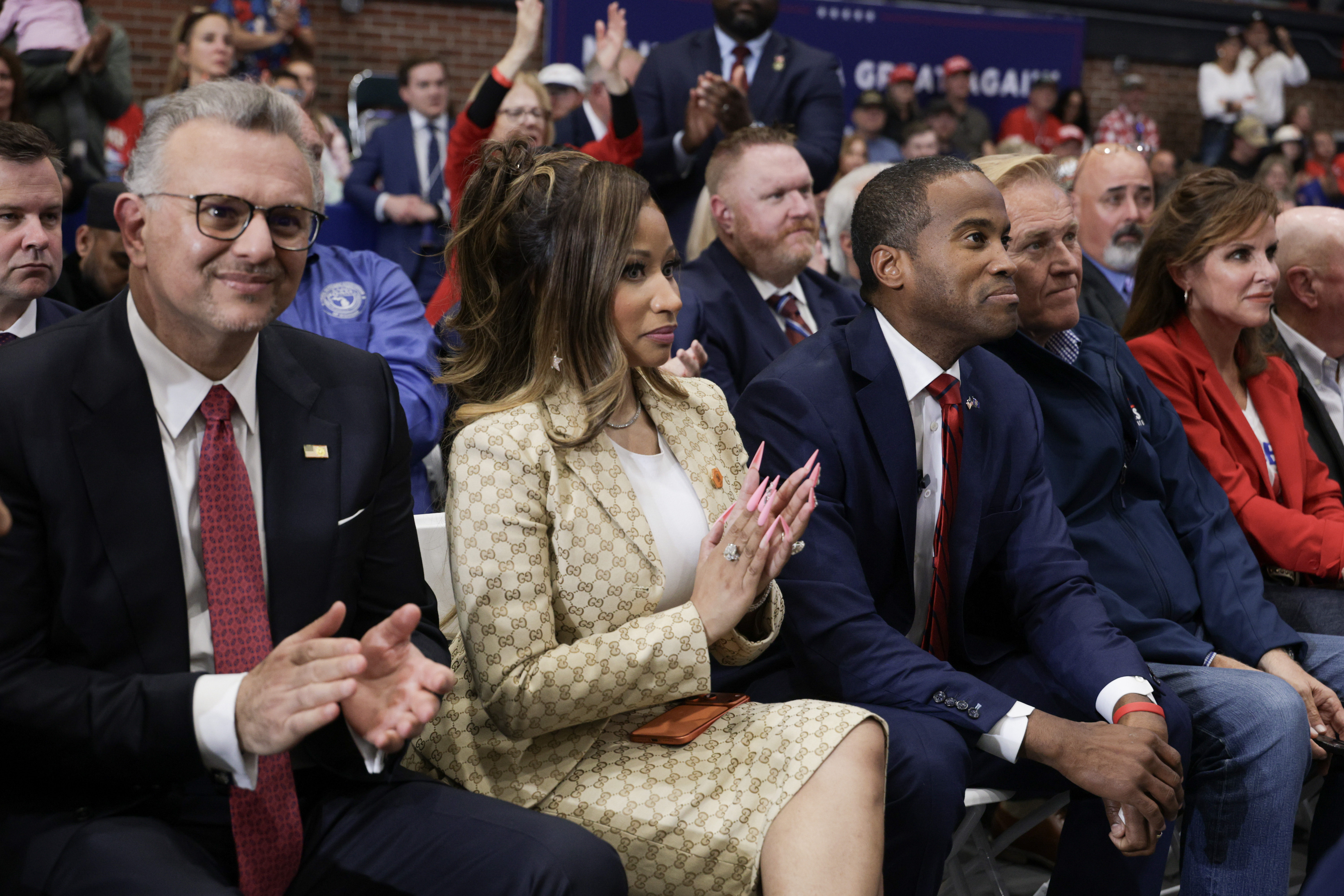 Nicki Minaj joins the applause from a front-row seat alongside other invited guests, while supporters behind her rise to their feet — a glimpse of the rapper's place among the rally's prominent attendees. | Source: Getty Images