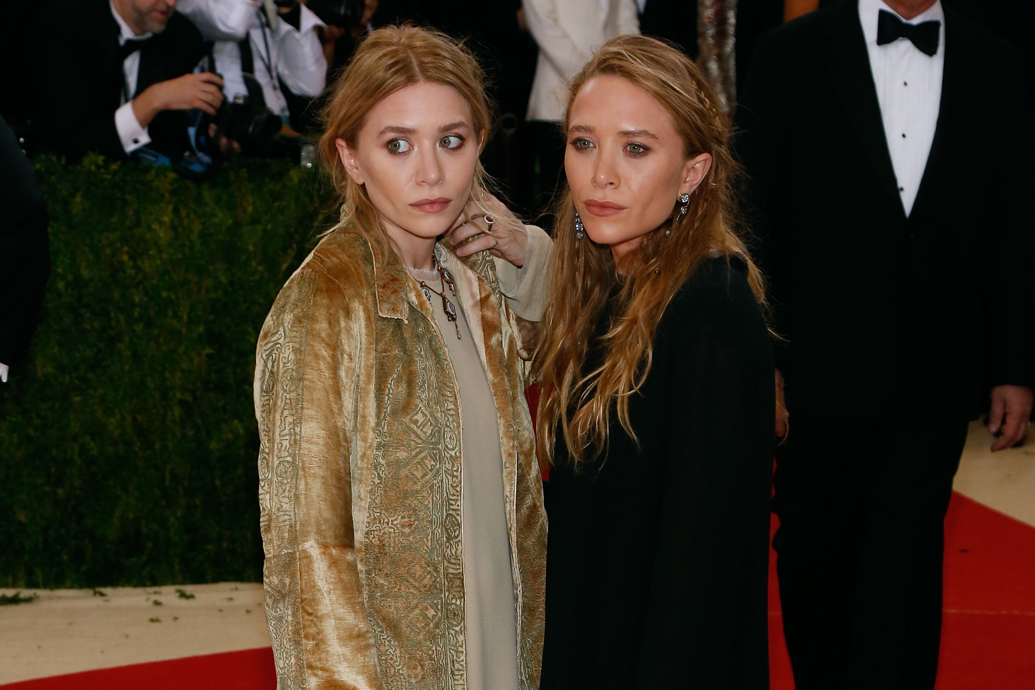 Sophisticated structure and refined composure defined 29-year-old Mary-Kate and Ashley Olsen at the May 2, 2016 Costume Institute Gala, where their serene faces framed by softly pulled-back hair and minimal makeup complemented their layered, vintage-inspired bohemian coats and dark ensembles.